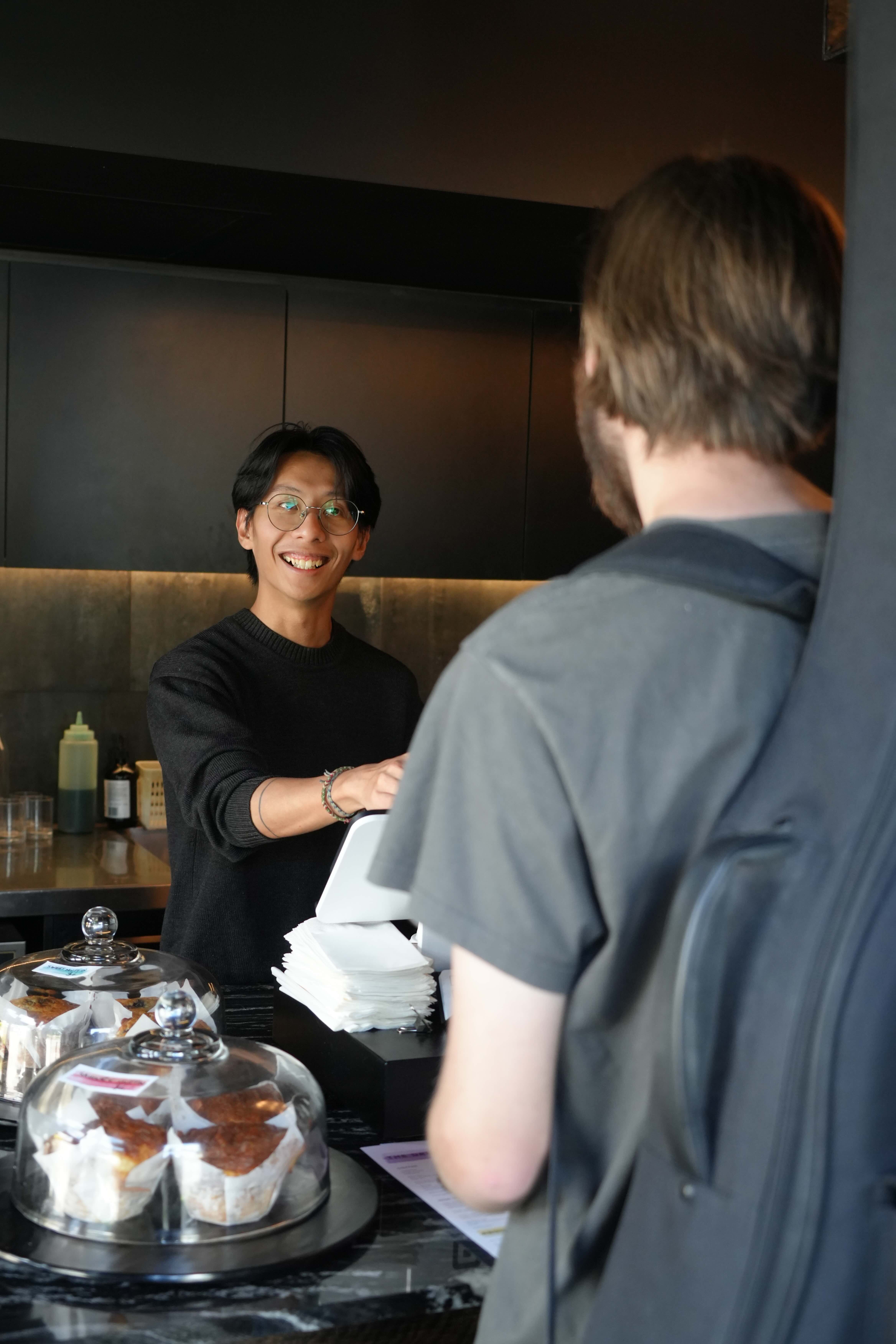 a young man serves a customer at a cafe
