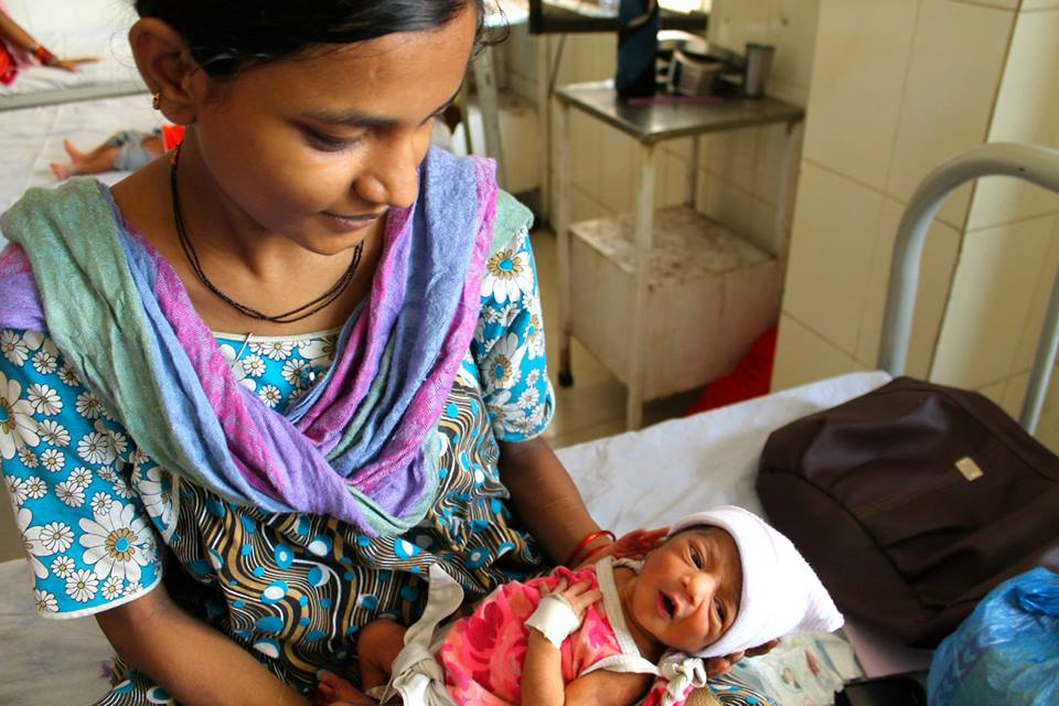 a mom in traditional clothes holds a newborn baby