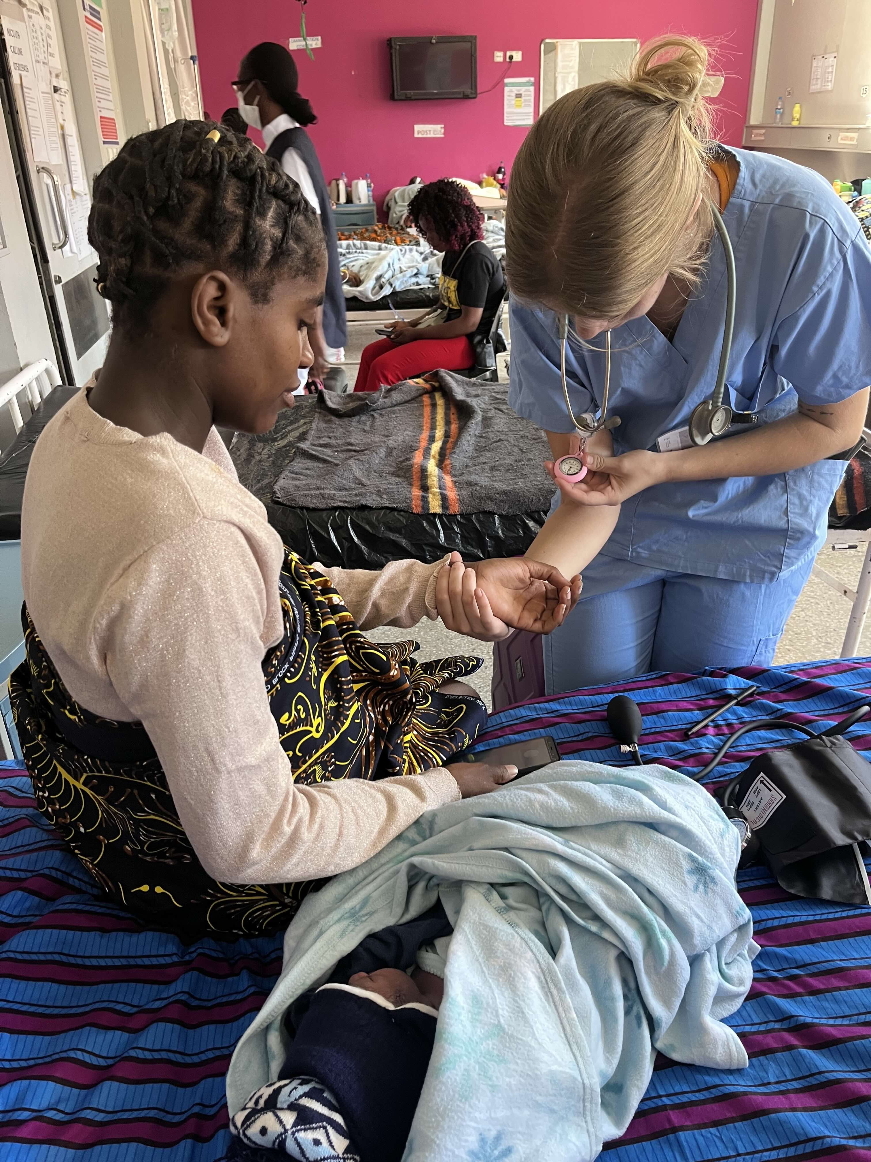 a health worker uses a stethoscope with a mom and baby