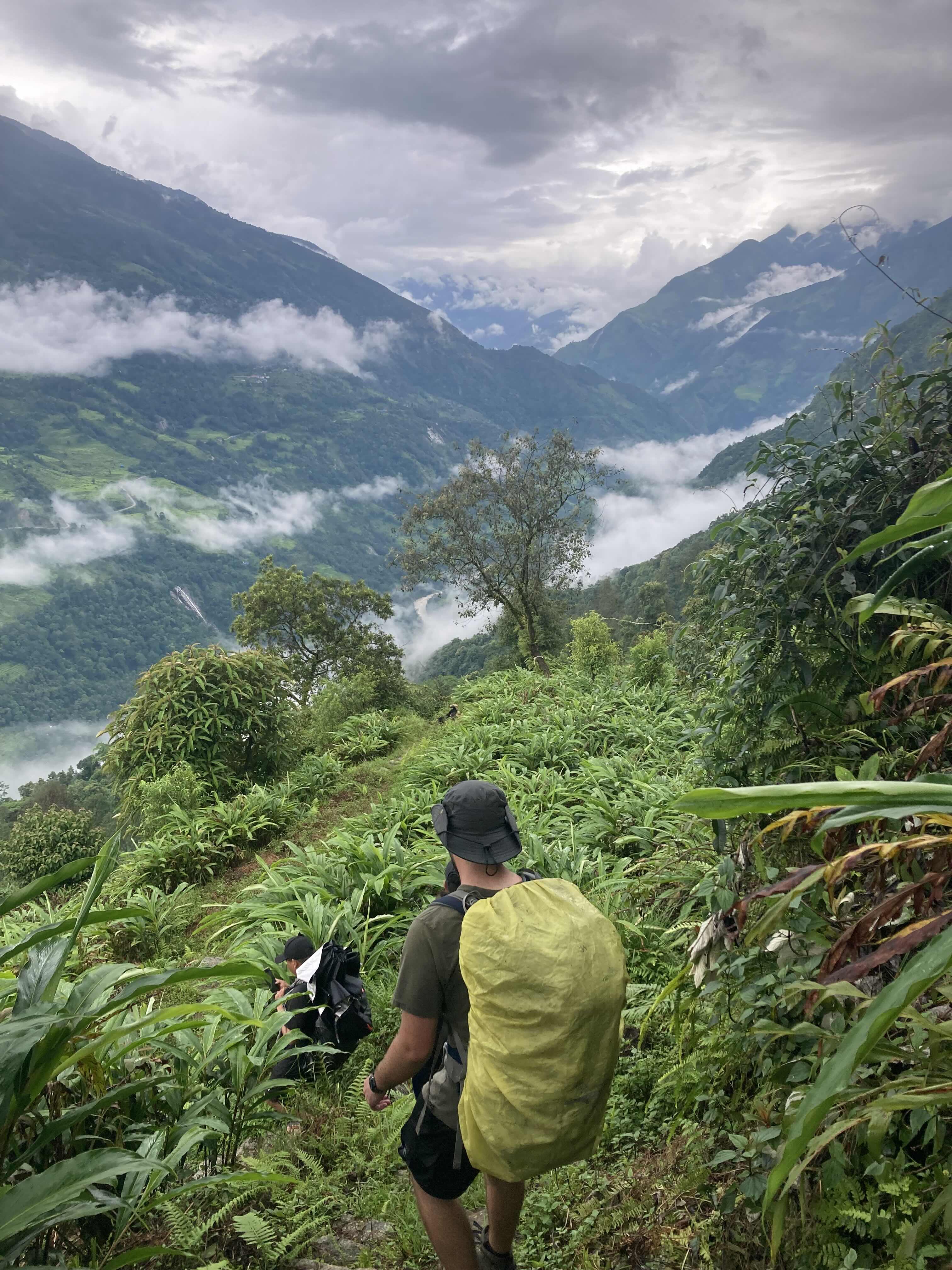 a man with a large backpack hikes into a misty valley