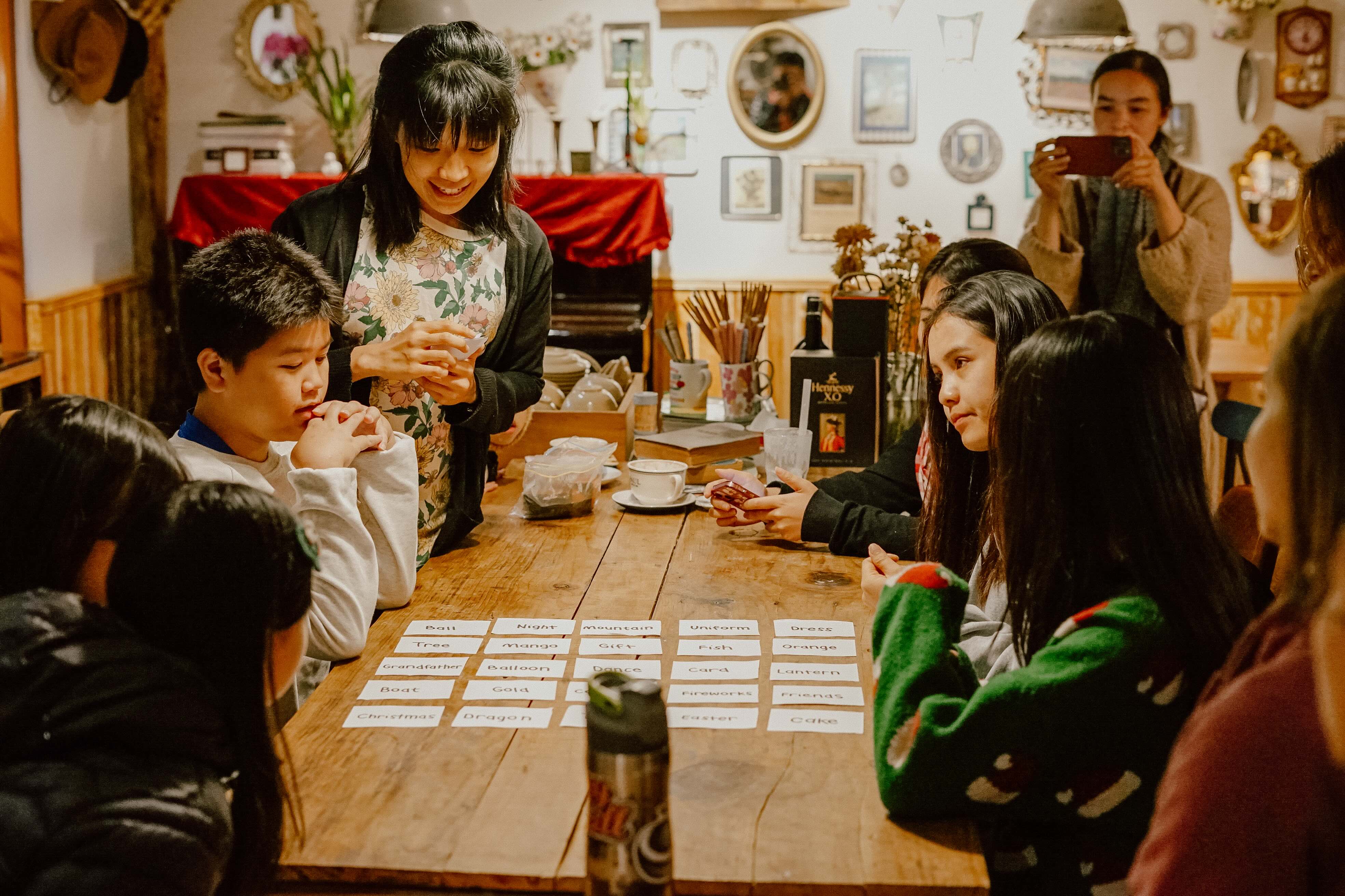 an adult teaches children with cards around a table