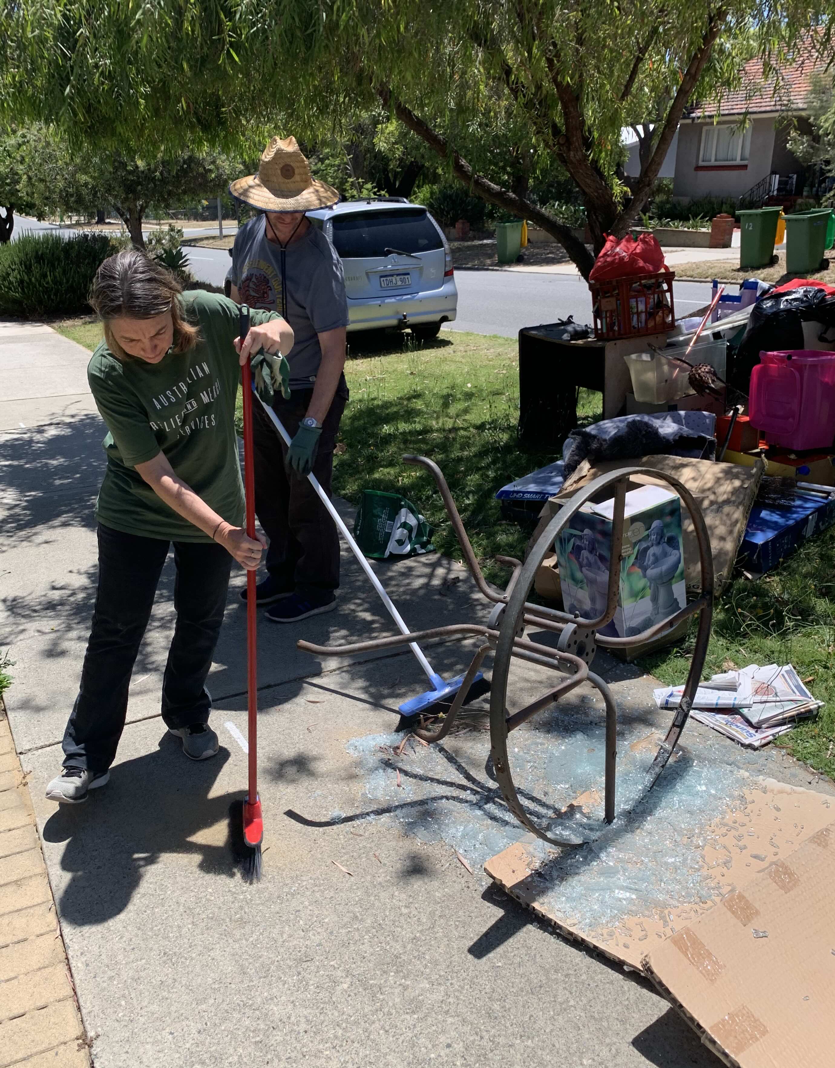 two adults clean up rubbish outside