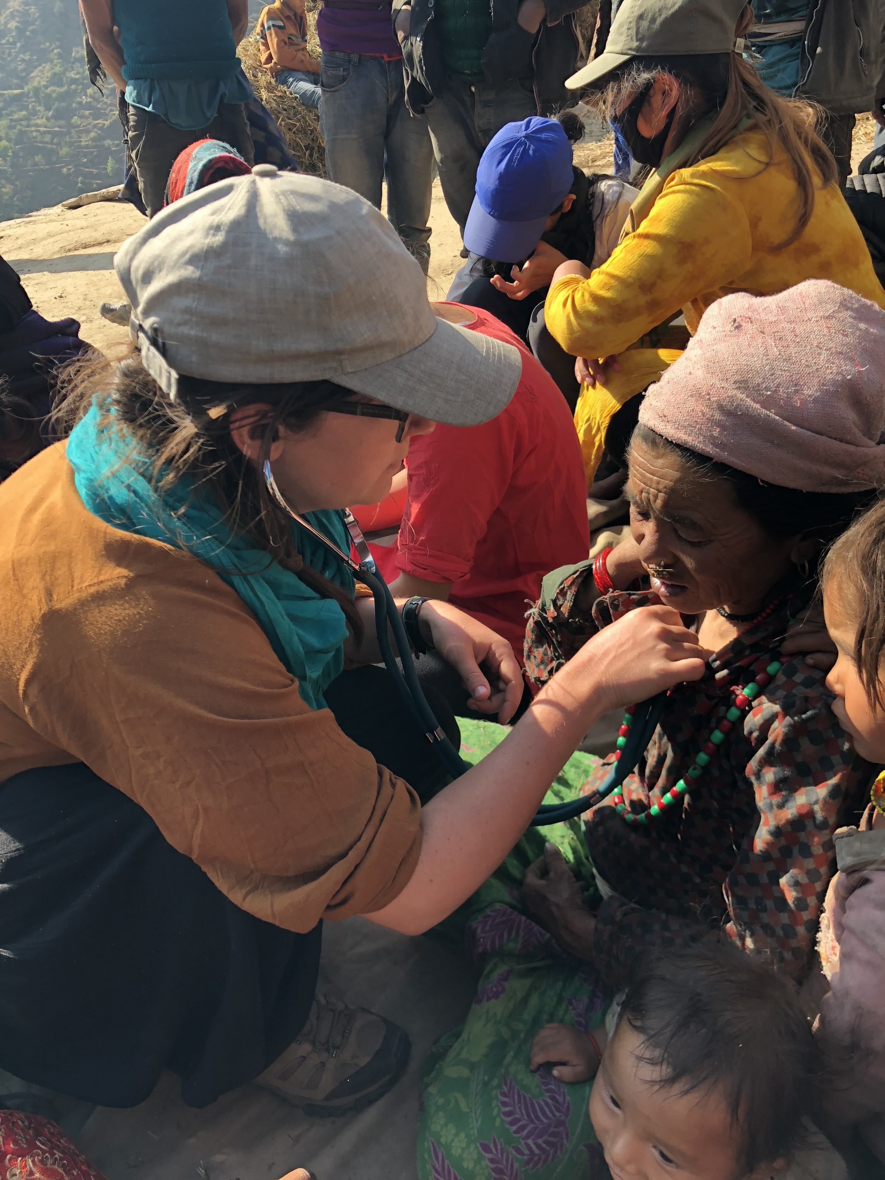 a woman listens to a villager's heart with a stethoscope