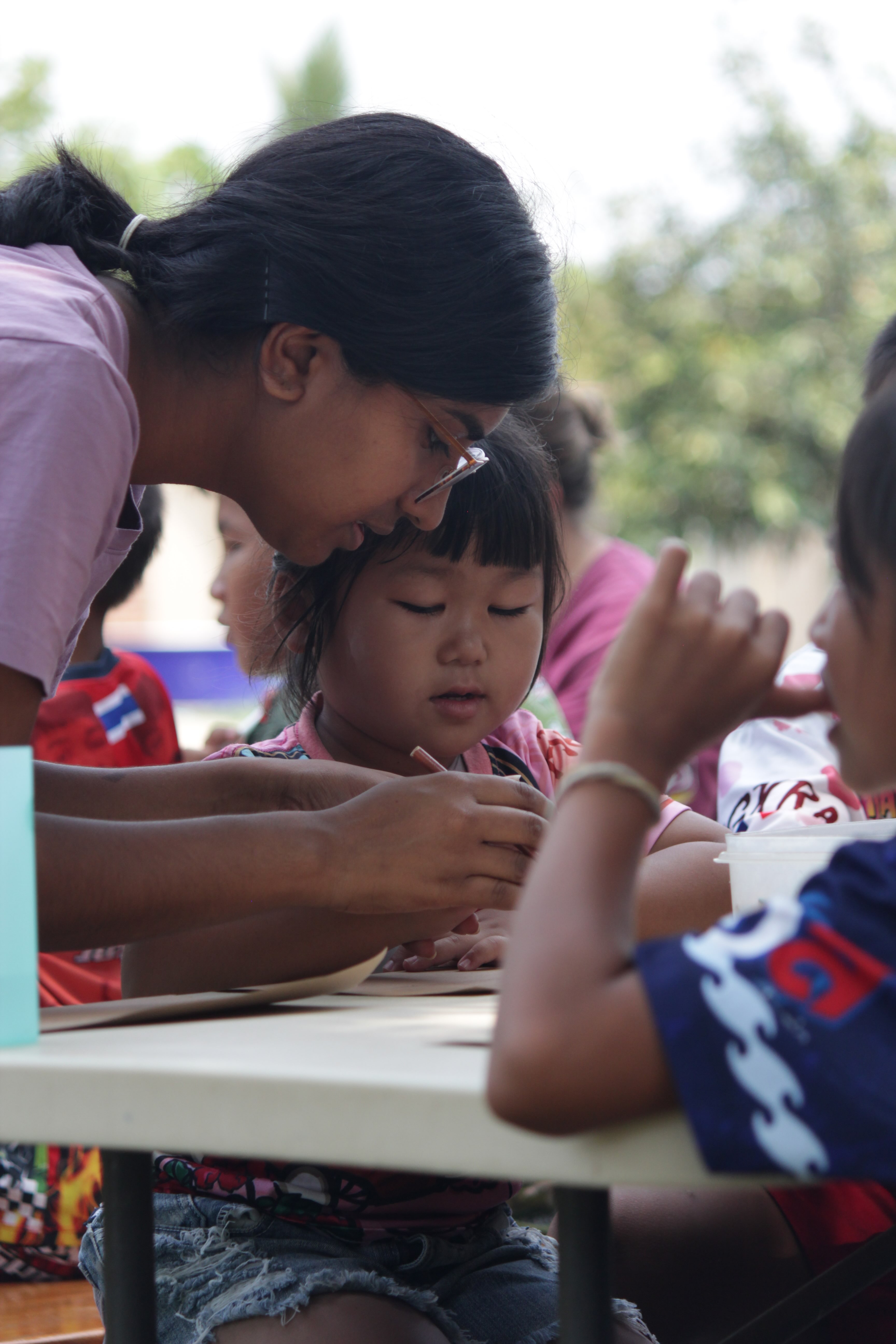 a teacher assists children at a table outside