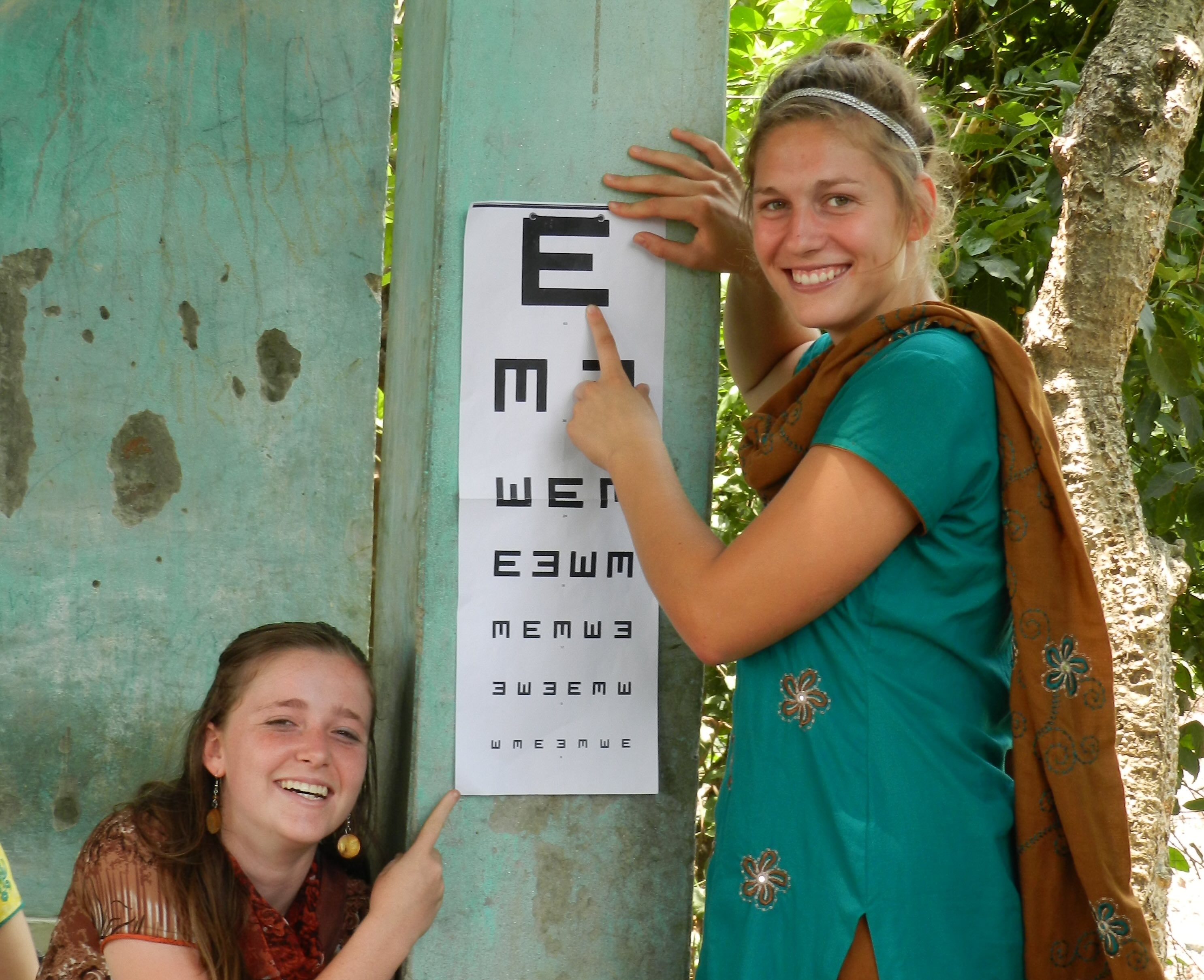 two smiling girls point to an eye chart