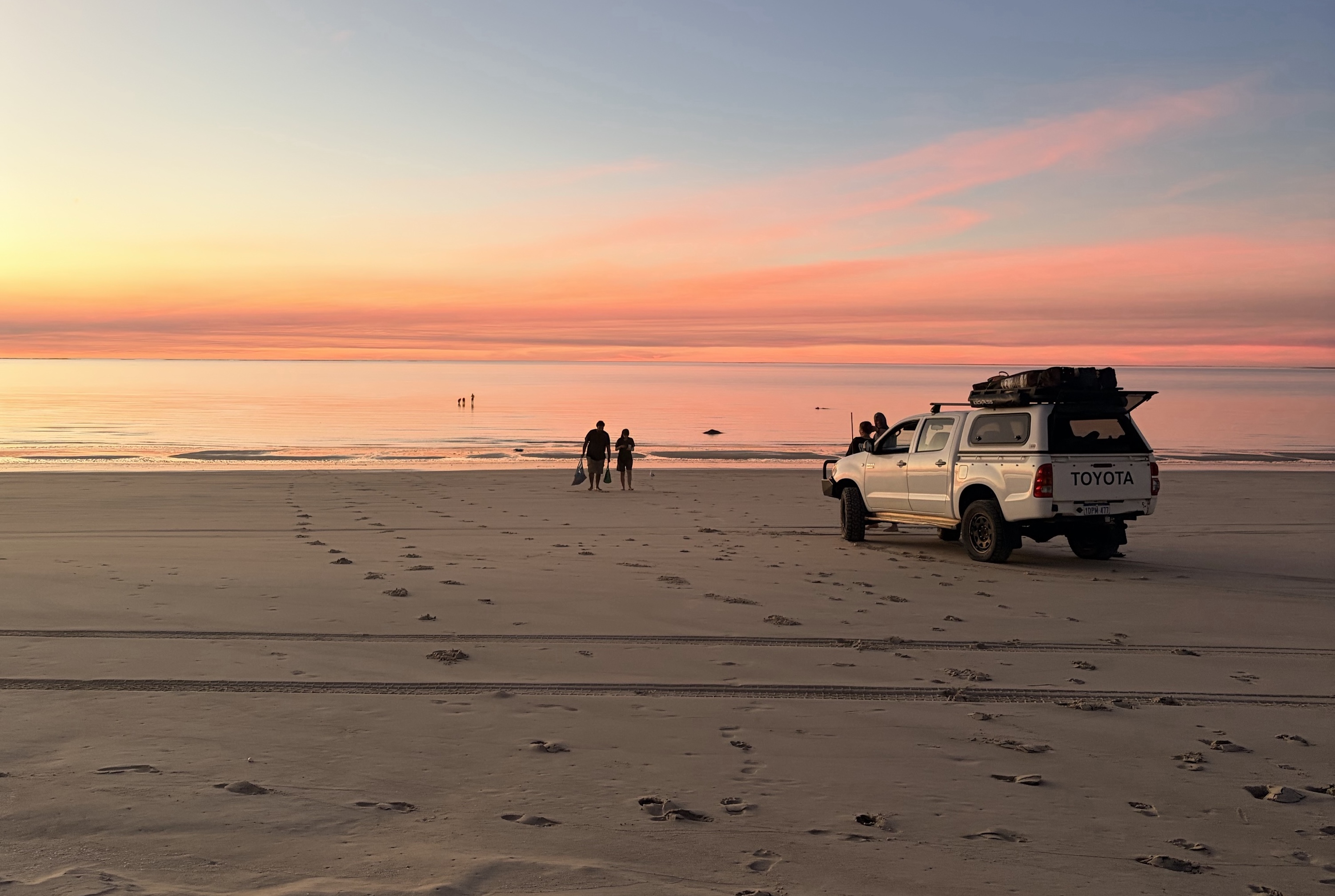 a 4wd on a beach at sunset