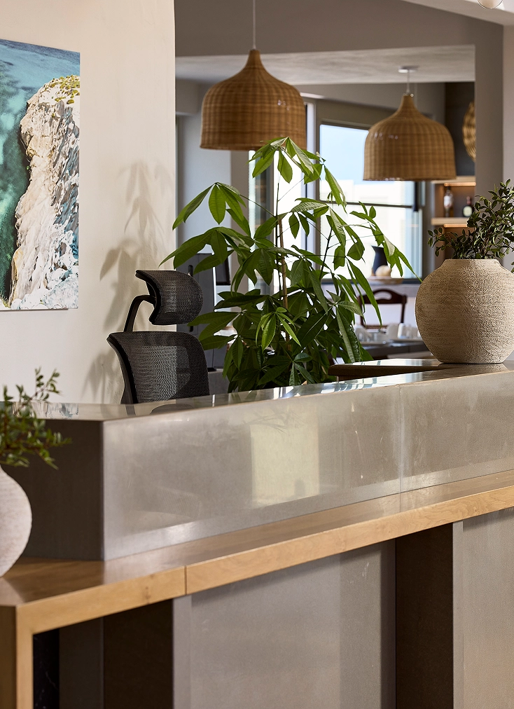 A desk featuring various plants and a vase surrounded by indoor cabinetry and a sink, set in a stylish kitchen interior.