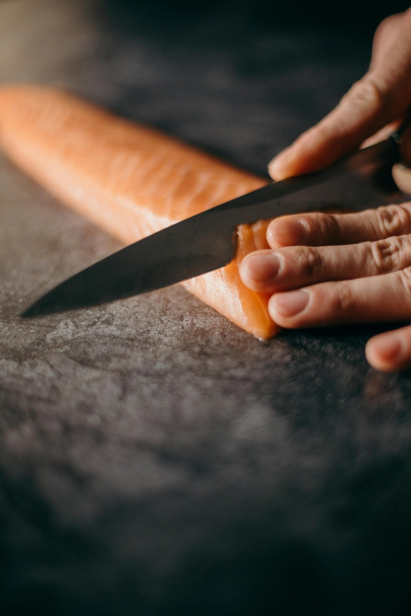 Close-up of a chef slicing salmon with extreme precision for fine dining