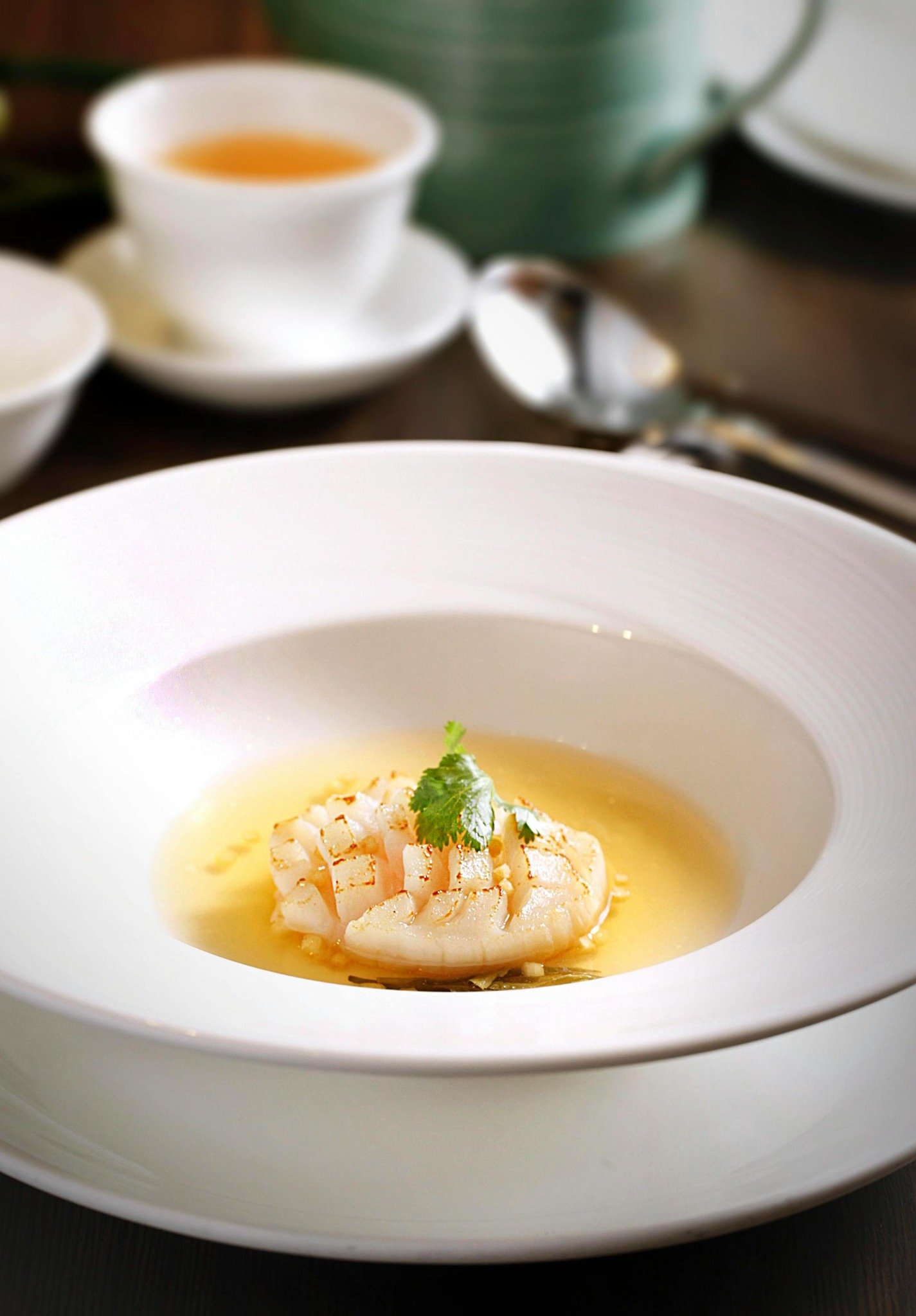 Delicately plated Michelin-starred seafood dish in clear broth