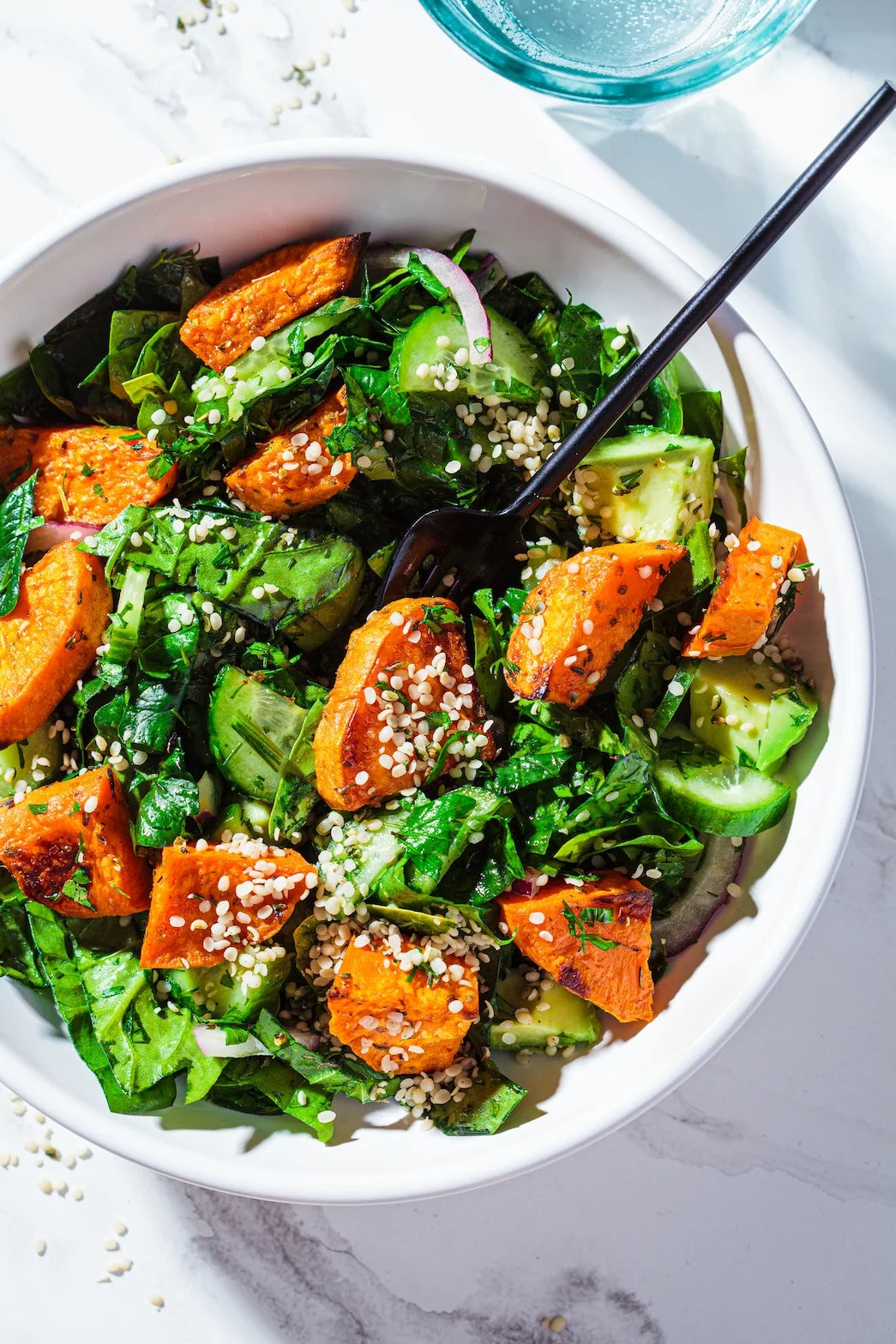 Bowl of baked sweet potato and green salad with sesame seeds, a vibrant plant-based performance meal designed for athletes.