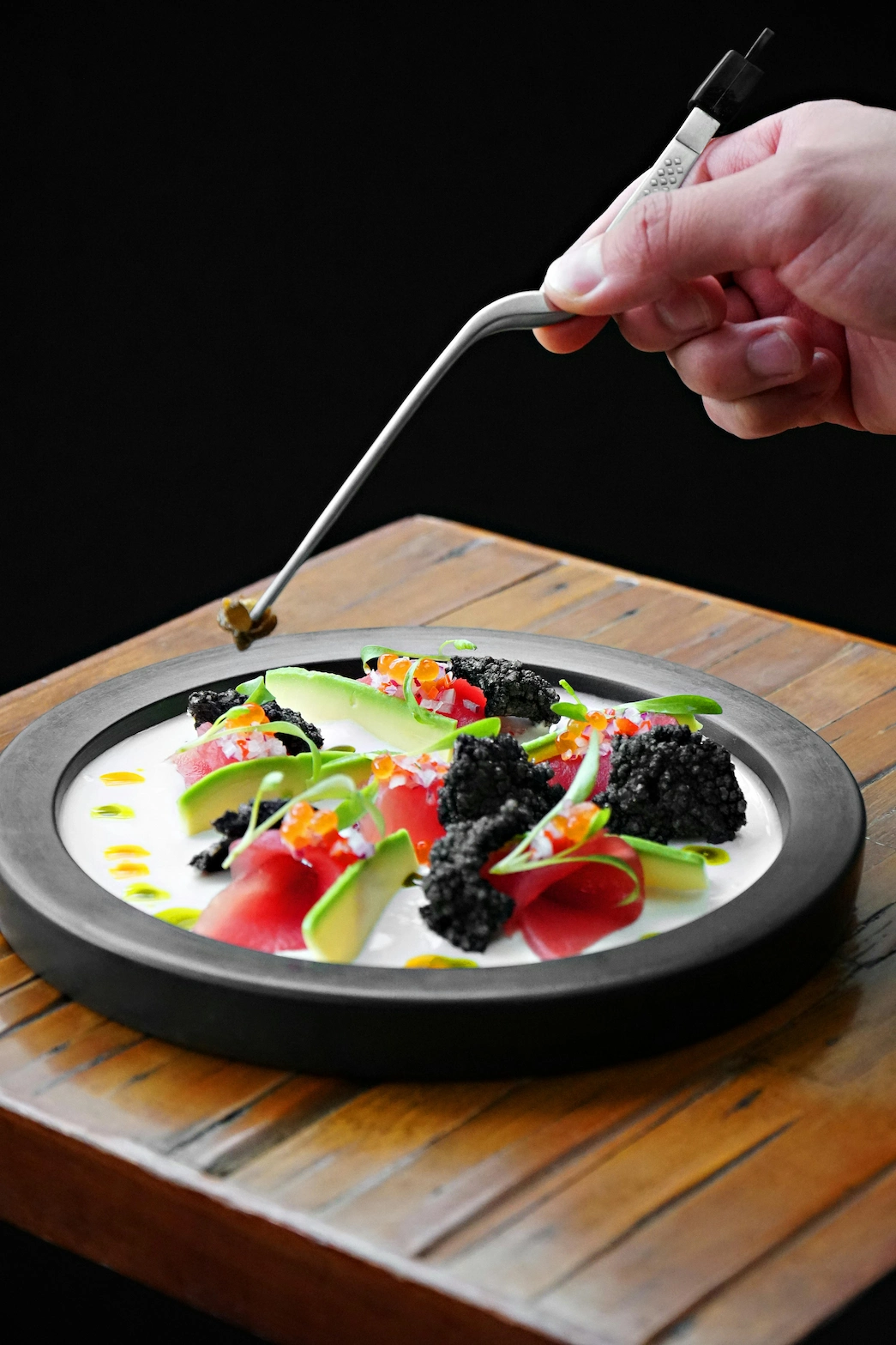 Michelin-trained private chef plating a fine dining dish with precision using tweezers, showcasing culinary artistry and attention to detail