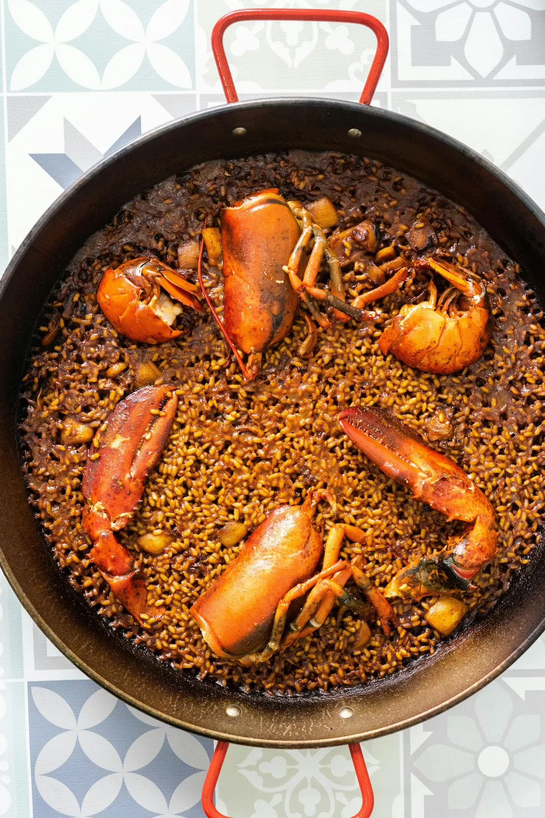 Traditional Spanish lobster paella in a rustic pan, representing authentic European private chef cuisine.