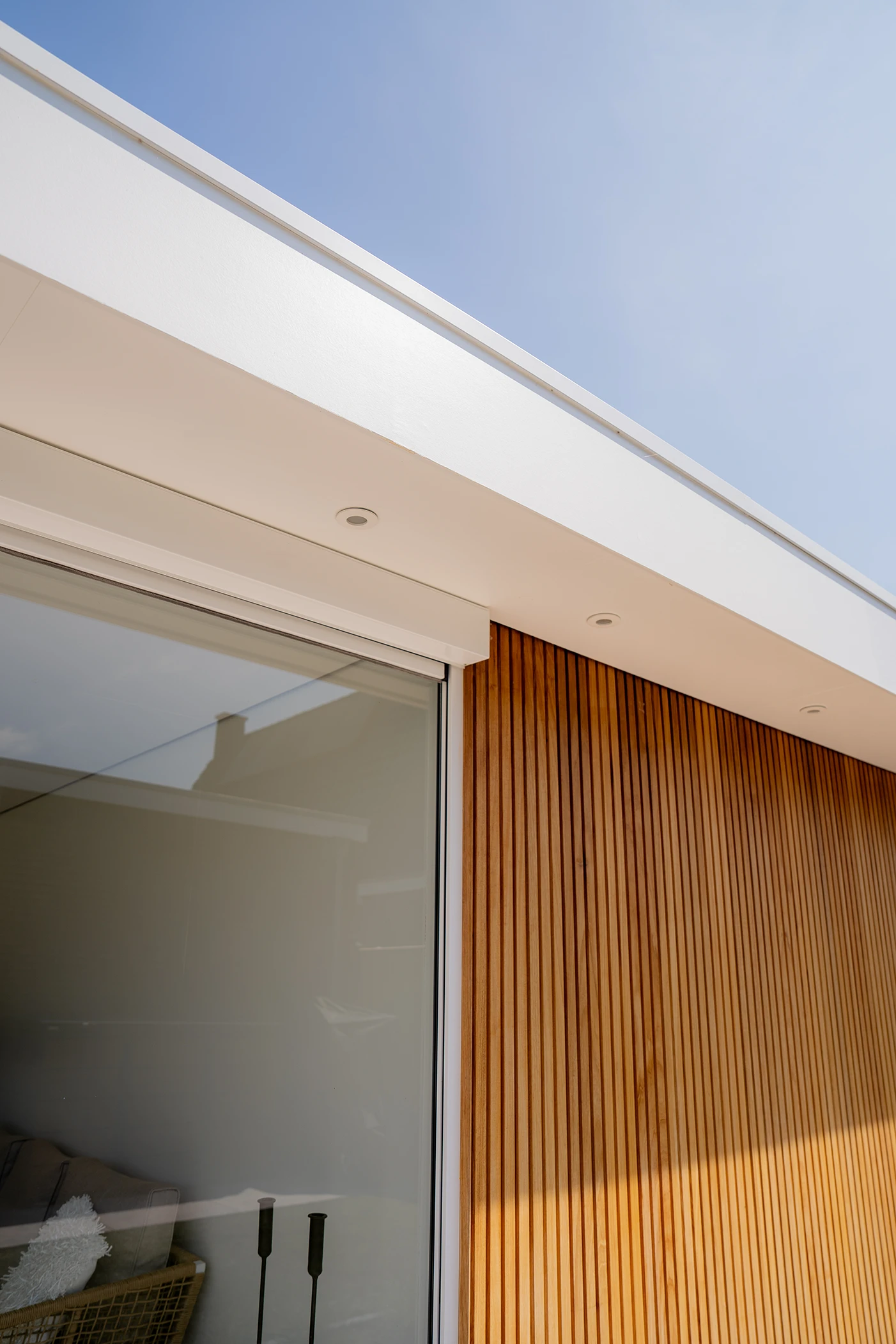 Close-up van een douglas overkapping met glazen wanden en spots in het witte dak.