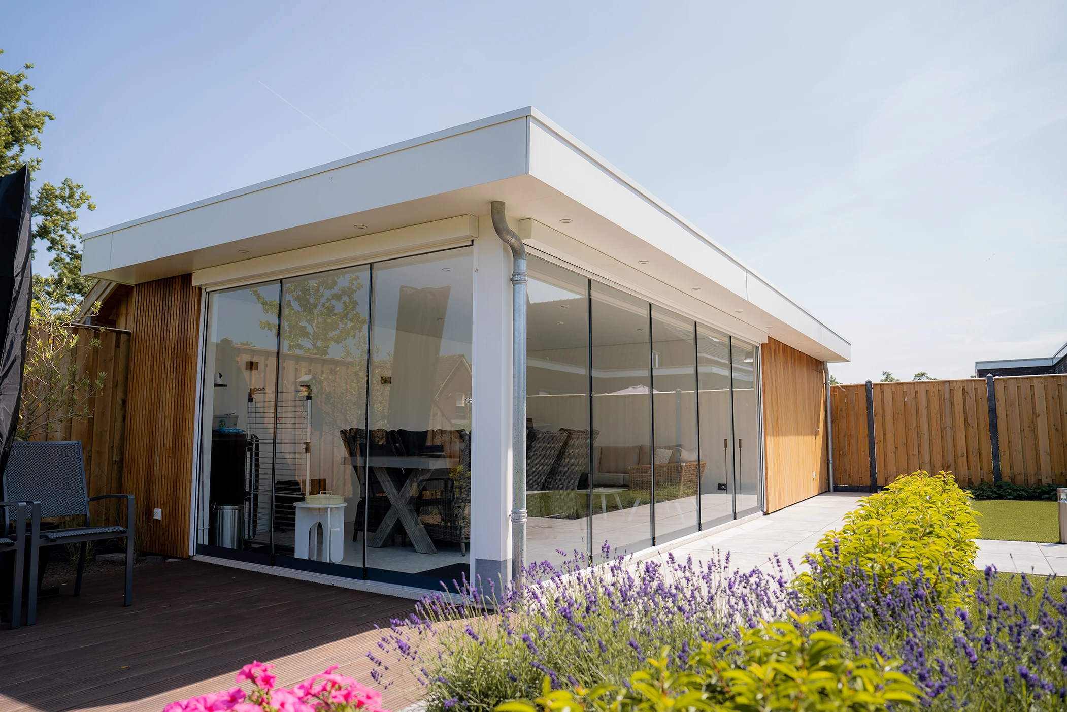 Overkapping met glazen wanden en een wit platdak met planen in de achtergrond