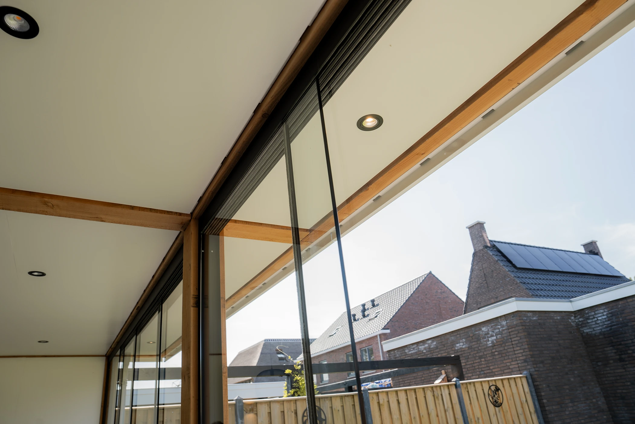 Close-up van een luxe overkaping met glazen wanden en spotlights op een wit plafon