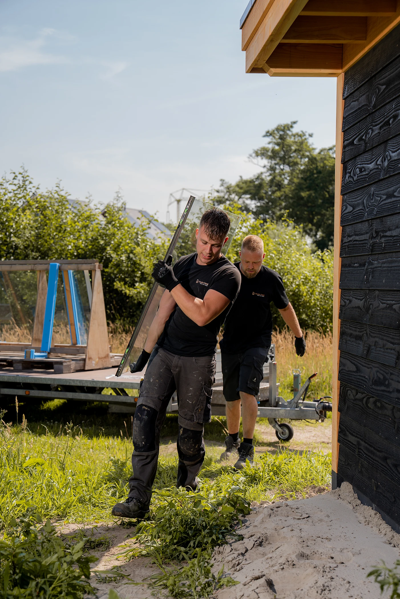 Jan Mark Kamphuis en Mitch Skipper aan het werk in een tuin met een douglas tuinkamer