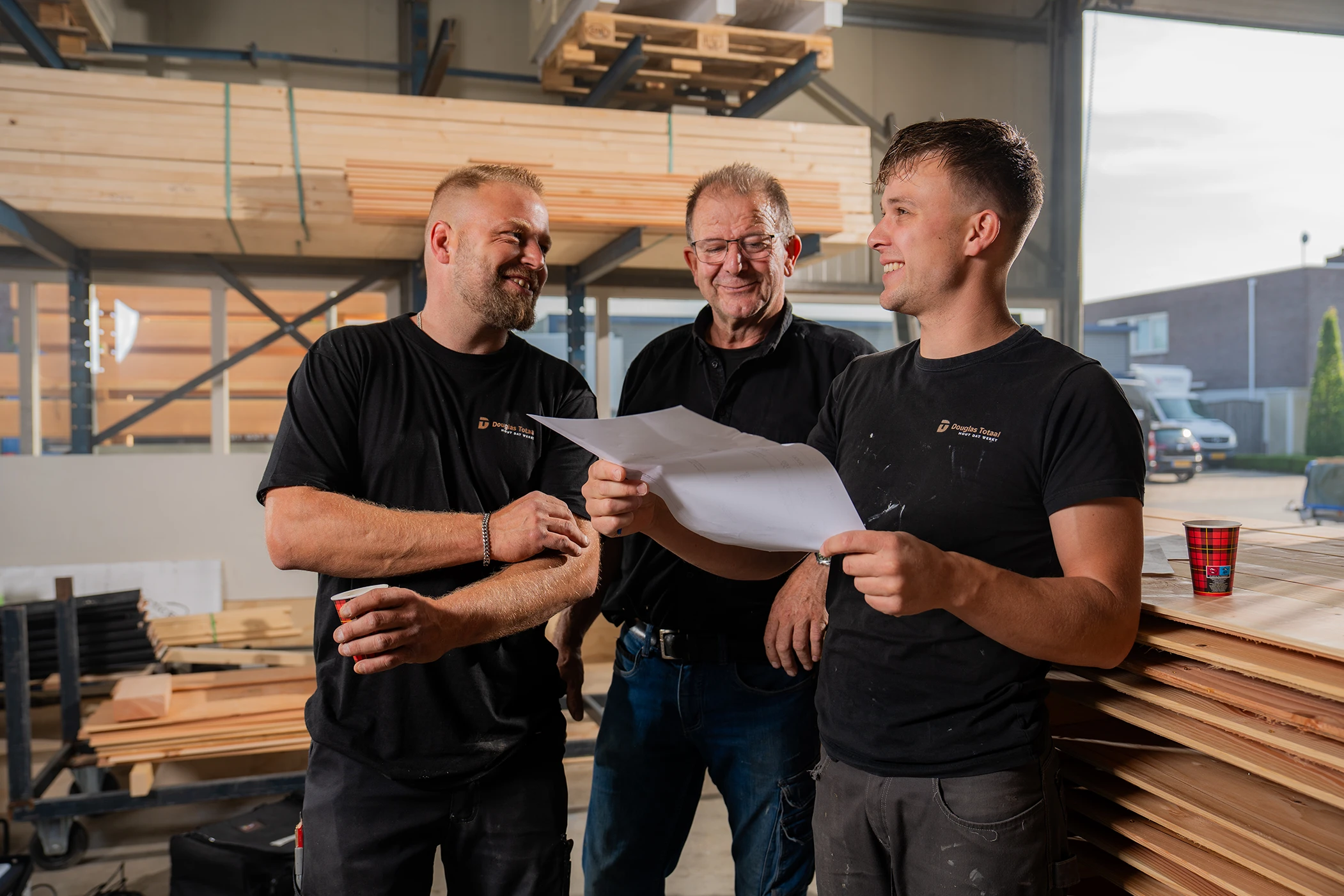Team van Douglas Totaal aan het werk met hun werkplaats in de achtergrond