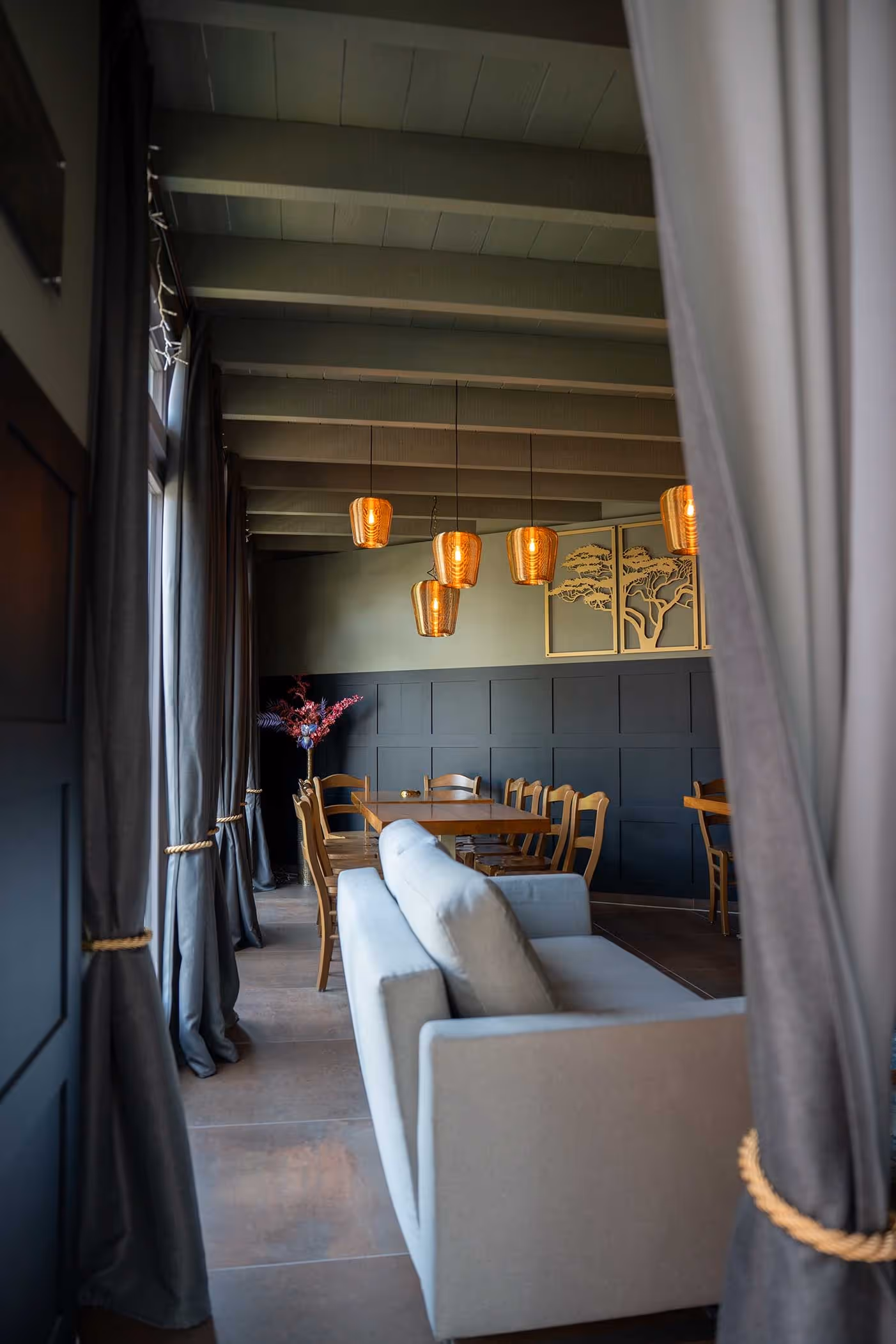 Binnenkant van een tuinkamer van dougoashout met een bank, gordijn en mooie lanpen