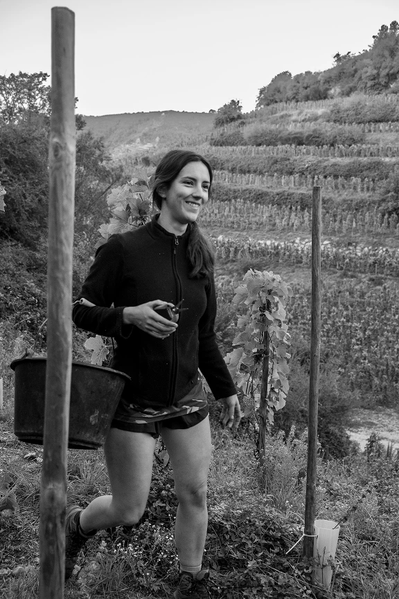 Daphné Chave souriante tenant un sécateur dans un vignoble en terrasse.