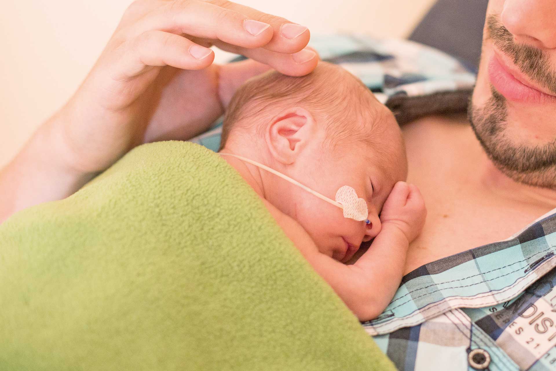 Neugeborenes liegt auf Vaters Brust.