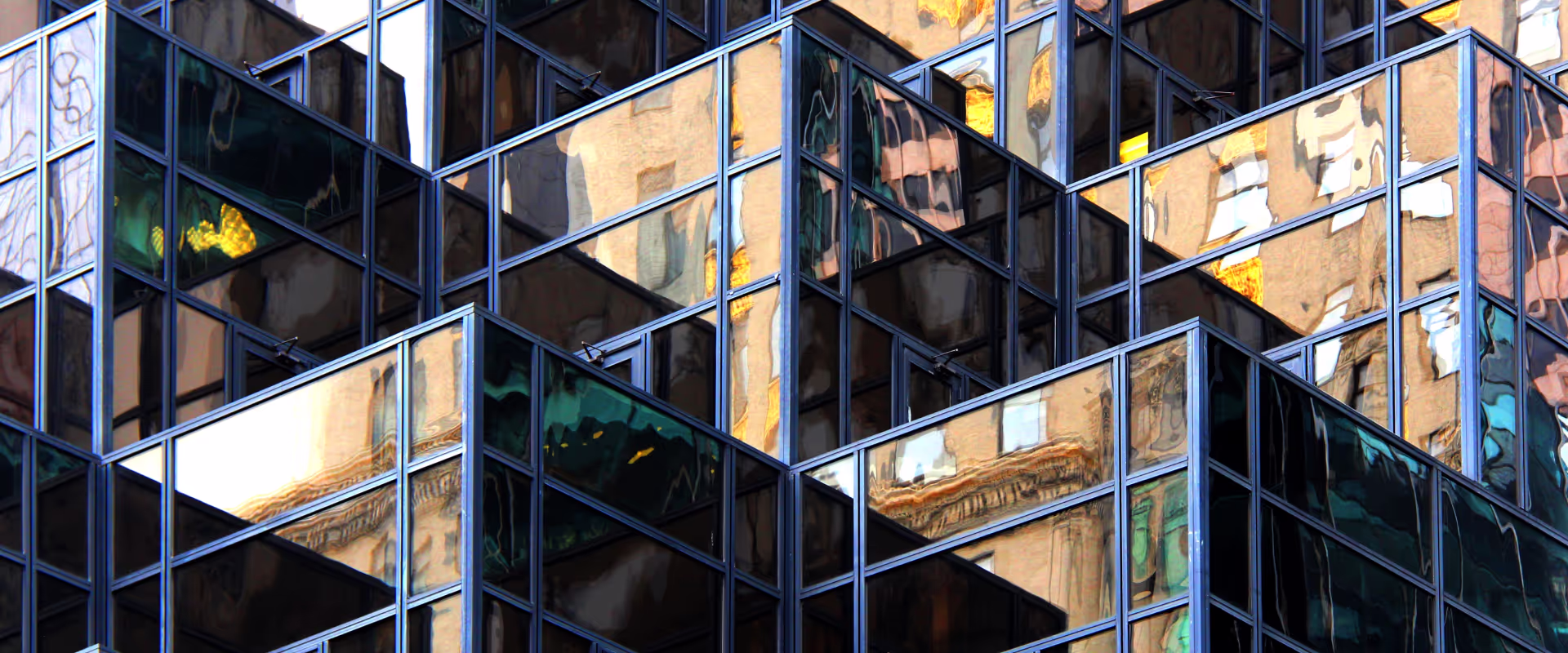 odern glass building with reflective surfaces, creating a distorted mirror effect of surrounding architecture. The geometric structure of the windows adds depth and abstraction to the urban scene.