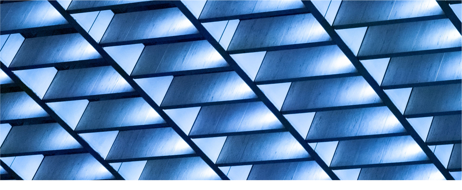 Geometric architectural pattern featuring illuminated triangular shapes in a modern building facade. The blue-toned lighting creates a futuristic and abstract aesthetic.