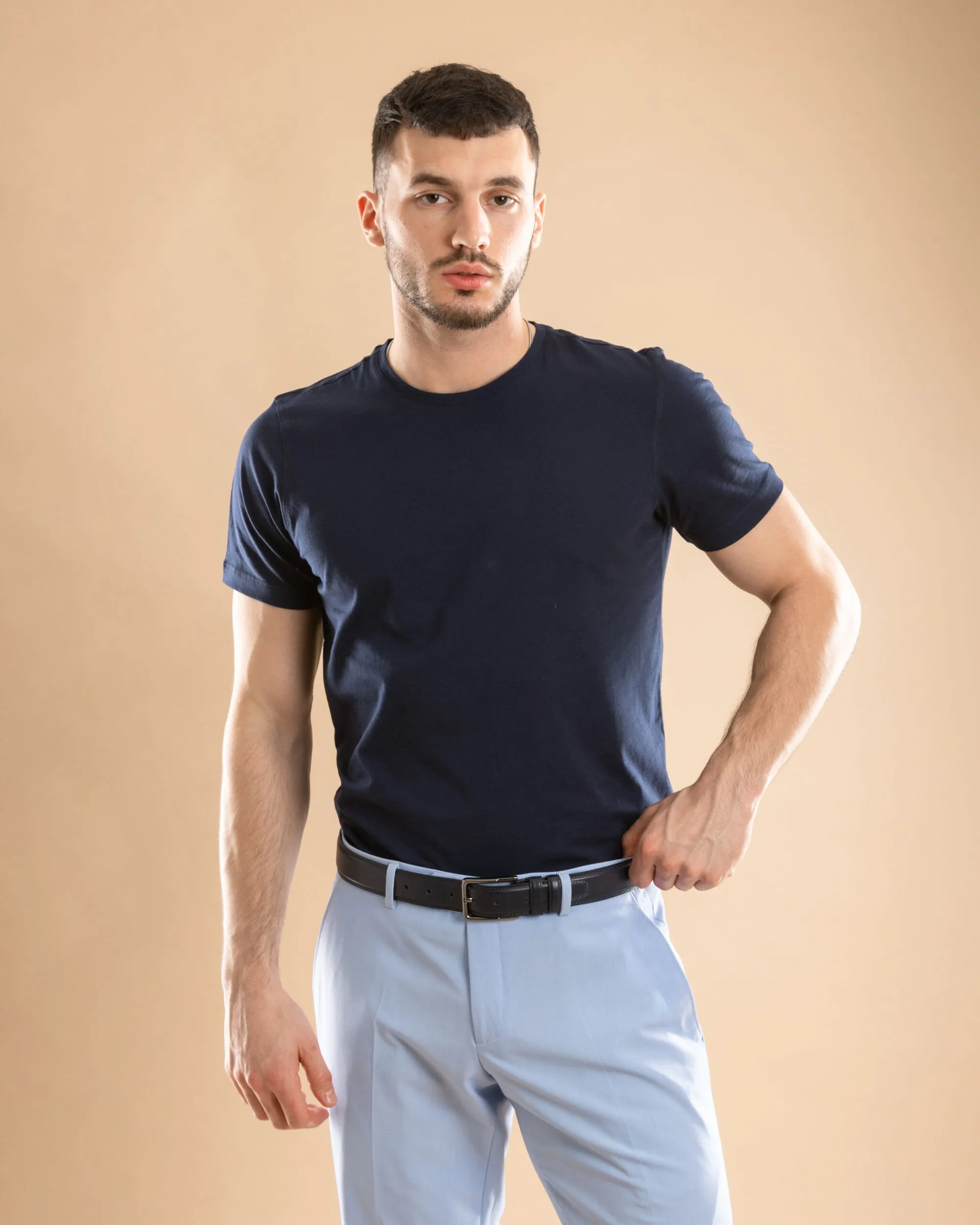 Man wearing a fitted navy t-shirt and tailored light blue trousers, representing casual fashion apparel manufactured by Prevent Group