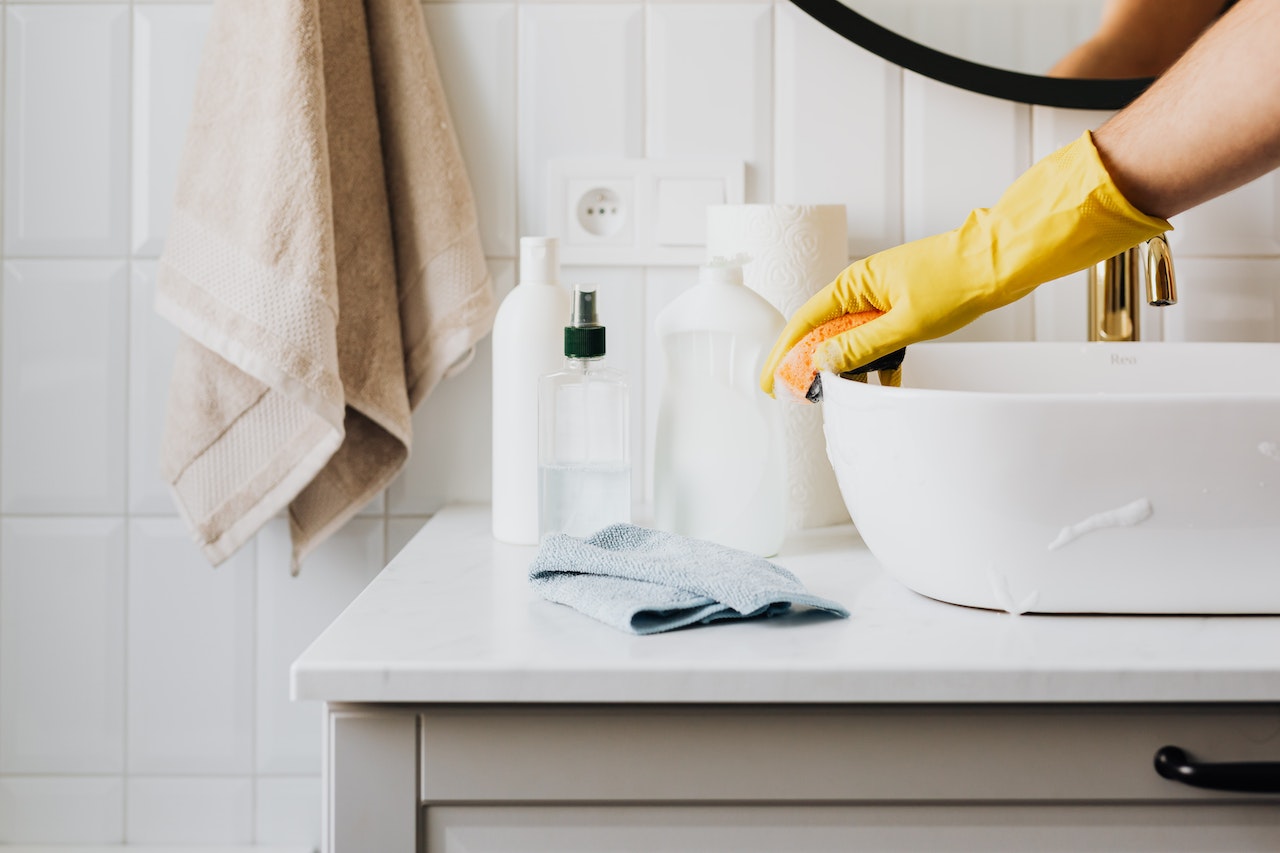 Hand cleaning white sink in house