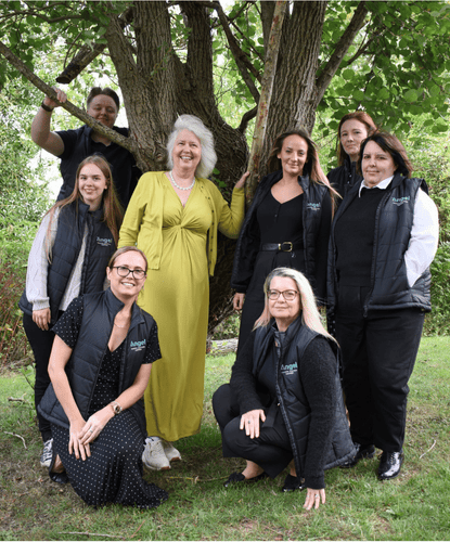 The Angel Accounting Team stood round a tree, all smiling at the camera outside their office in Alcester