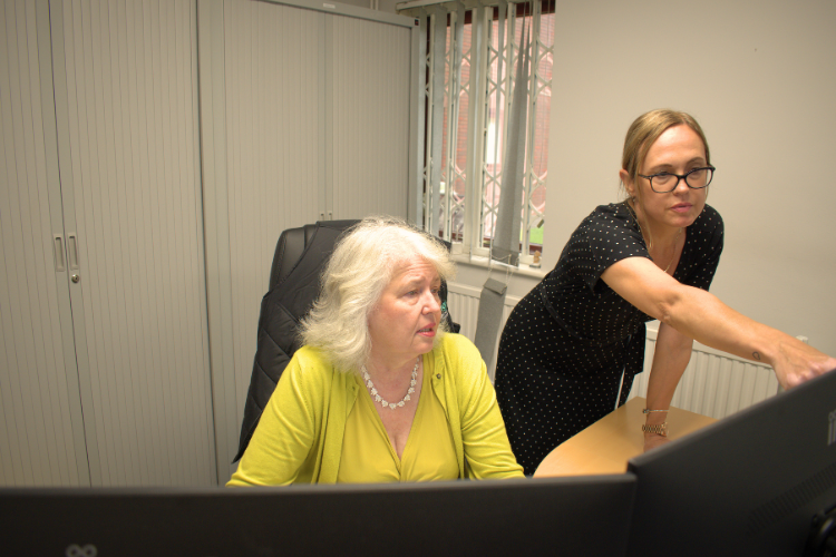 Person in a hooded jacket standing on a snow-covered rocky peak at night with a dark sky background.