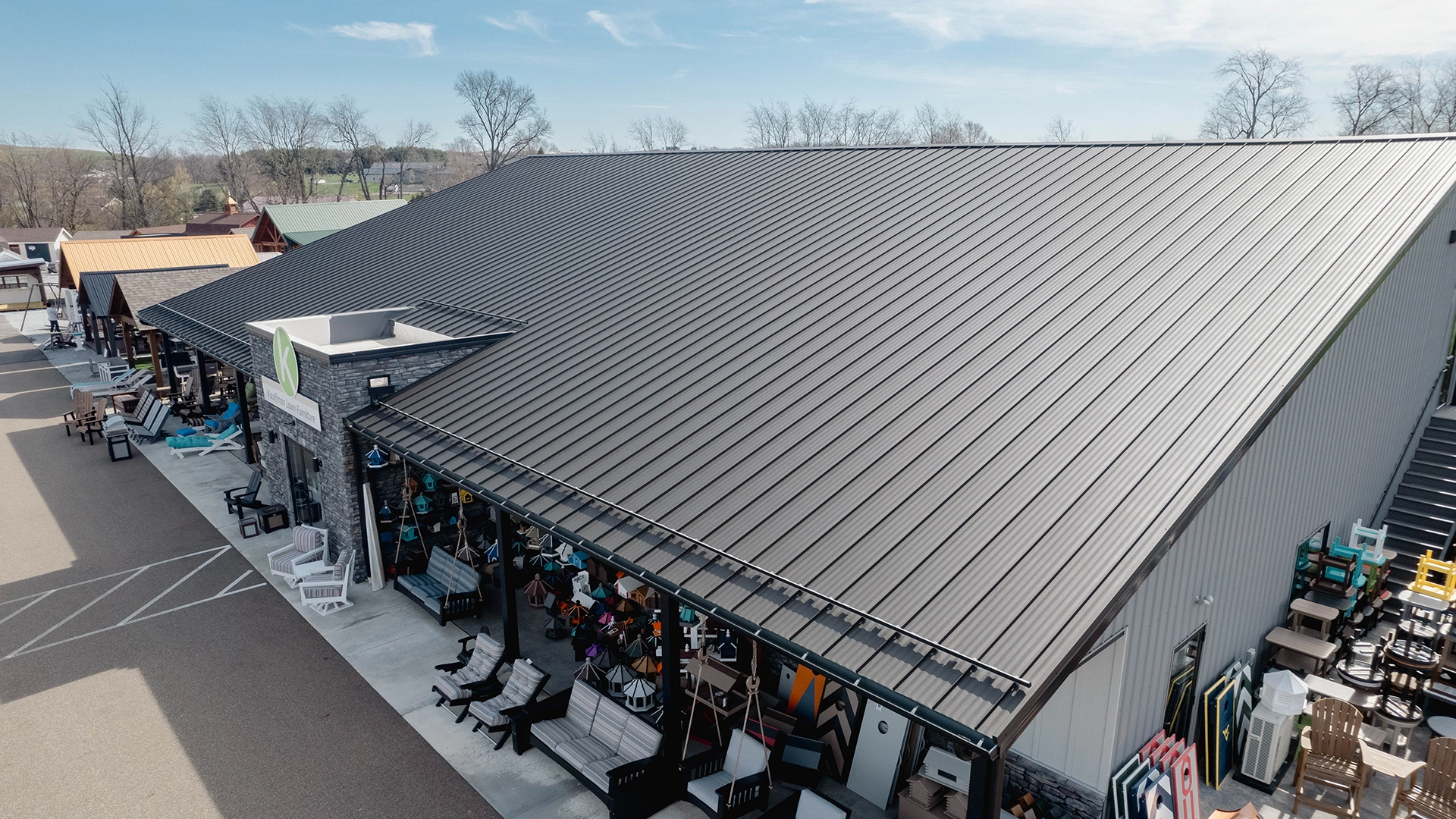 Standing seam metal roof installed on a large commercial retail building with seamless gutters and covered outdoor displays