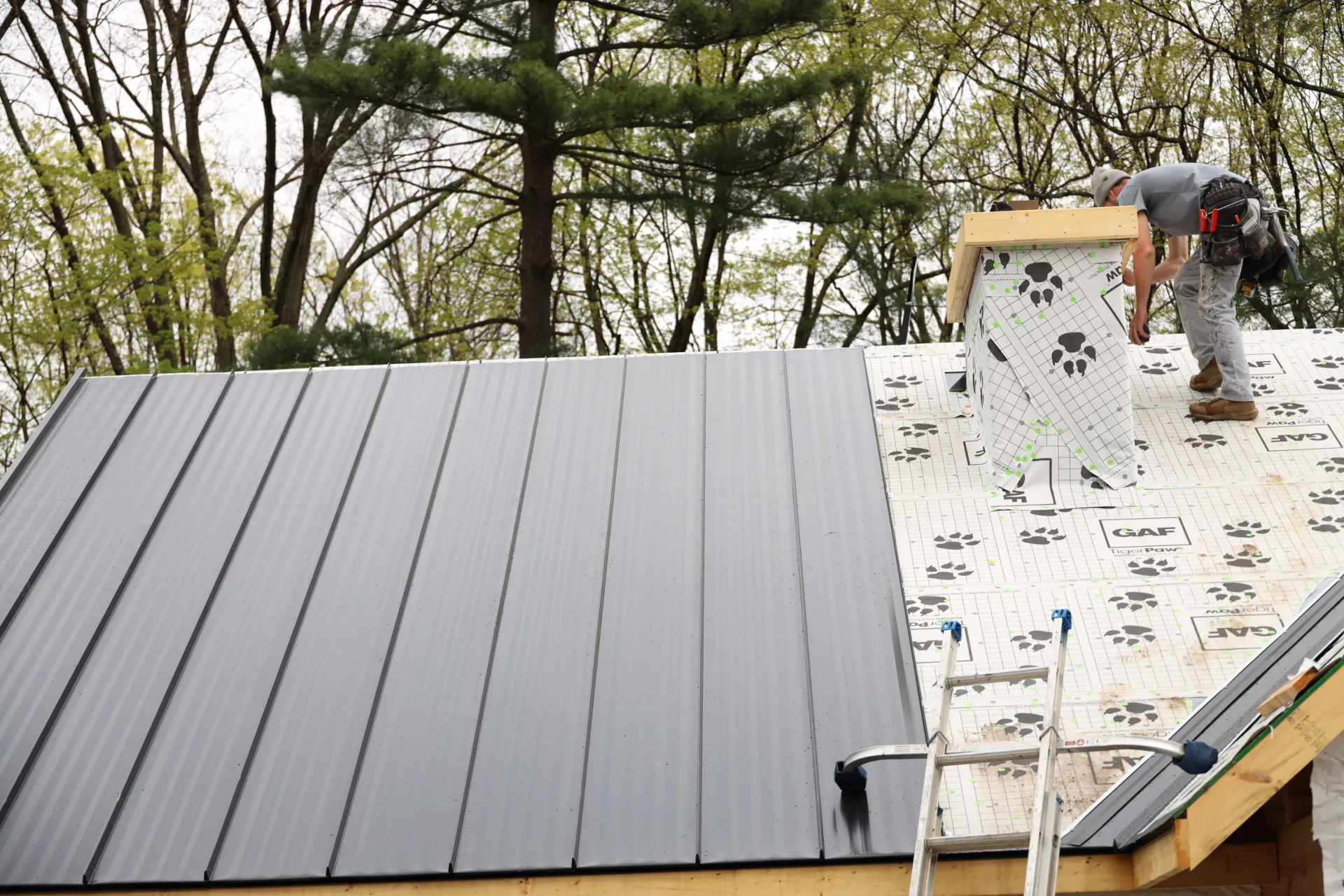 man working on a half done standing seam roof