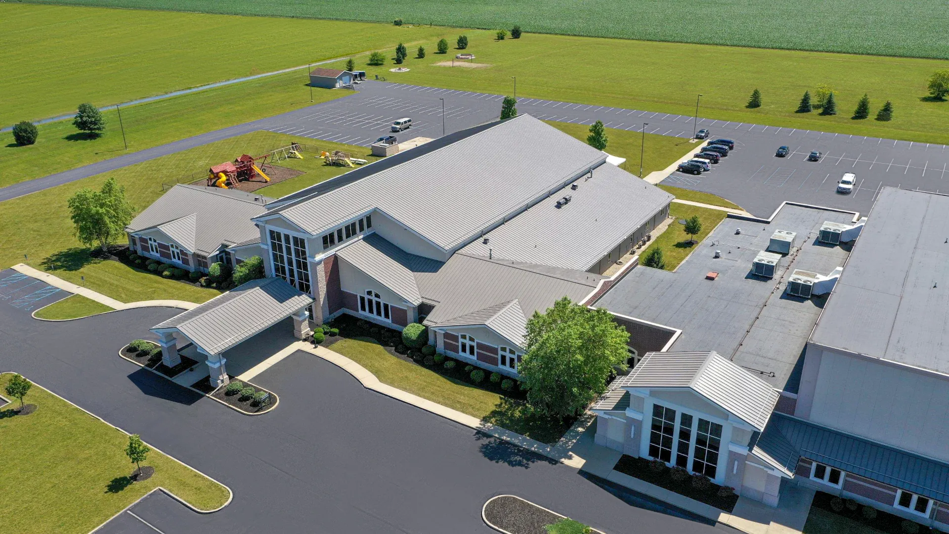 Aerial view of Gateway Church in Findlay, Ohio, featuring gray metal roofing, a covered entrance, and surrounding parking lots.