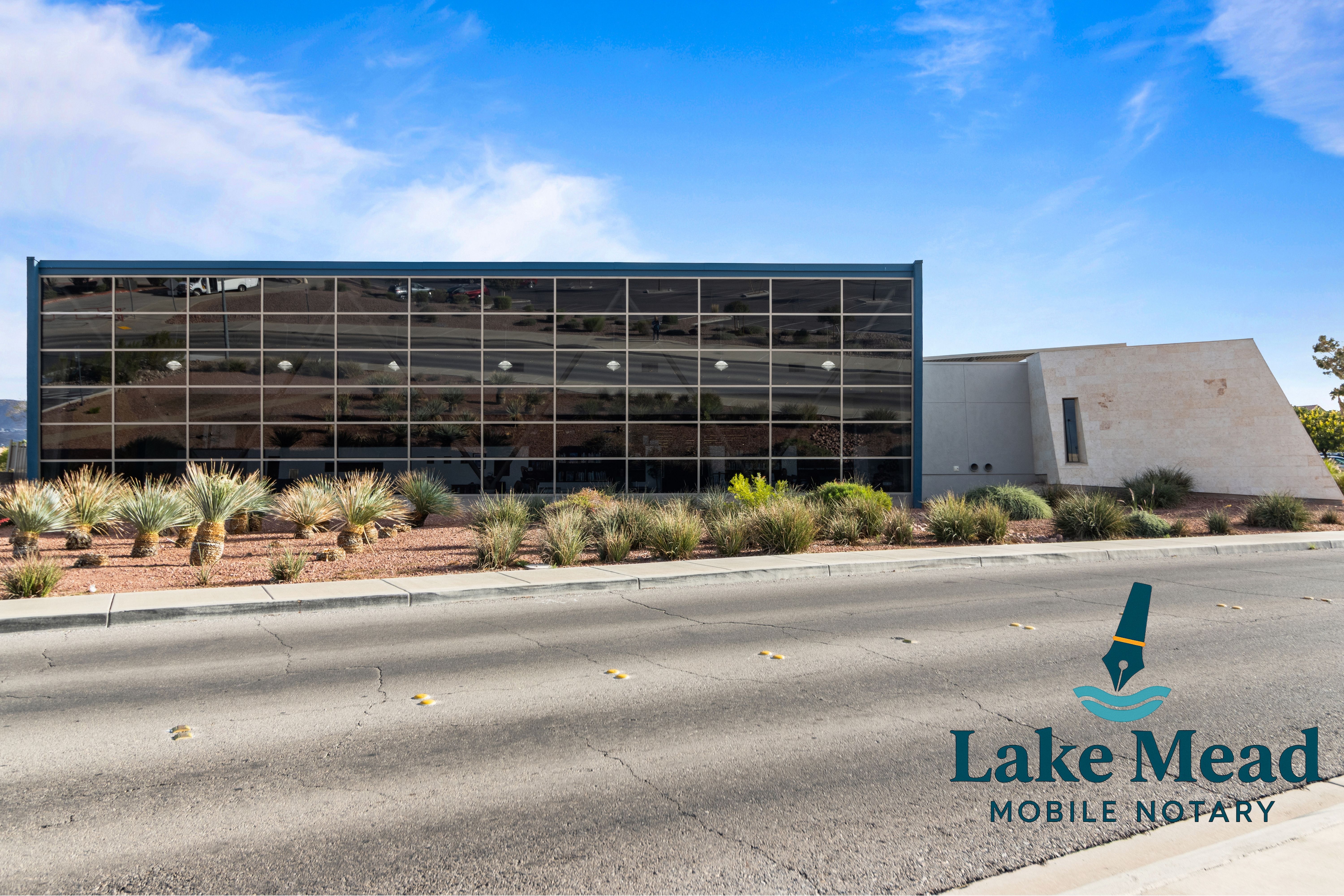 Modern glass civic building in Henderson; desert landscaping, clear sky, Lake Mead Mobile Notary logo visible.