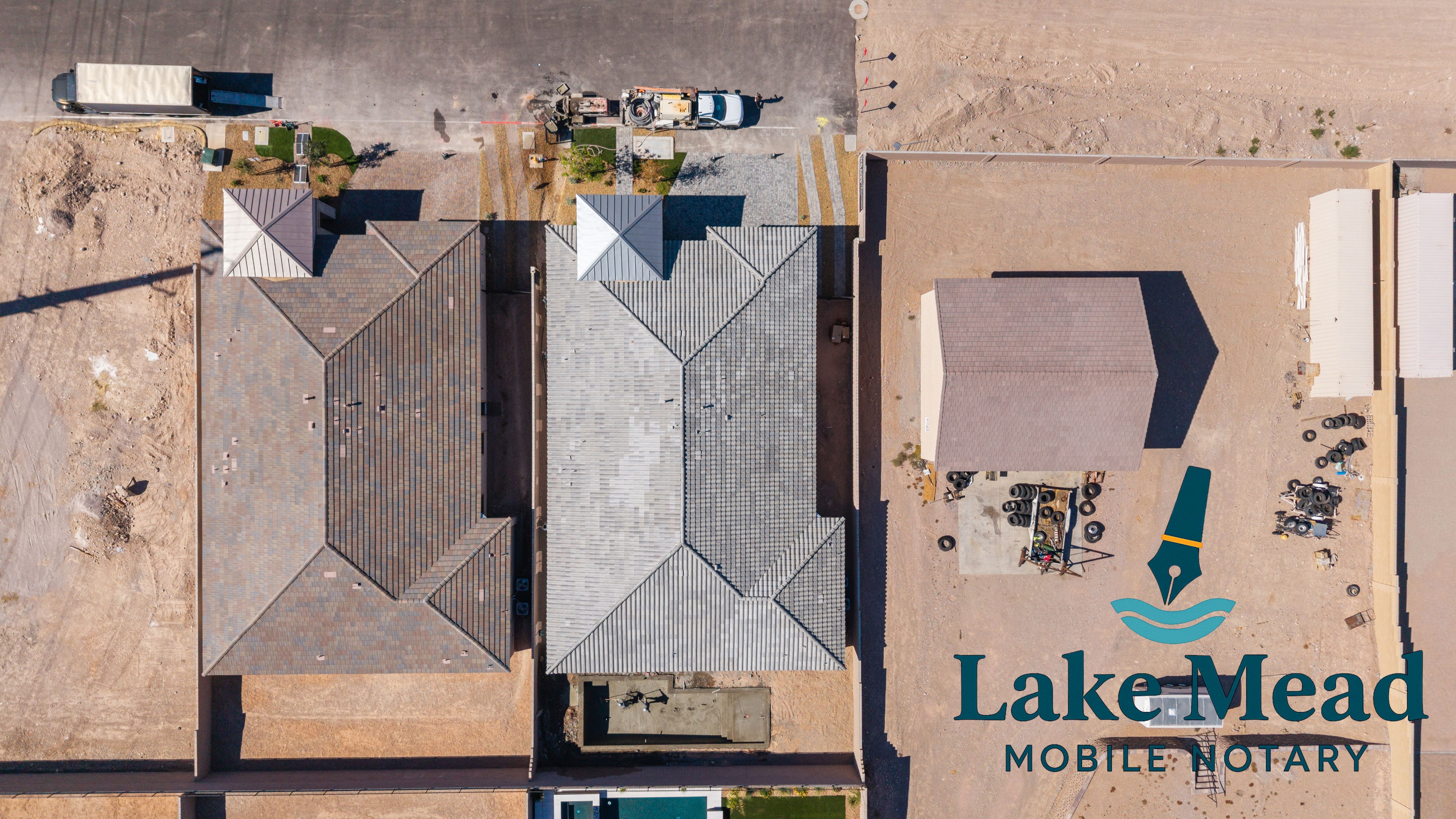 Vertical drone view of residential roofs in Henderson; lot lines visible, contractor trucks, Lake Mead Mobile Notary logo visible.