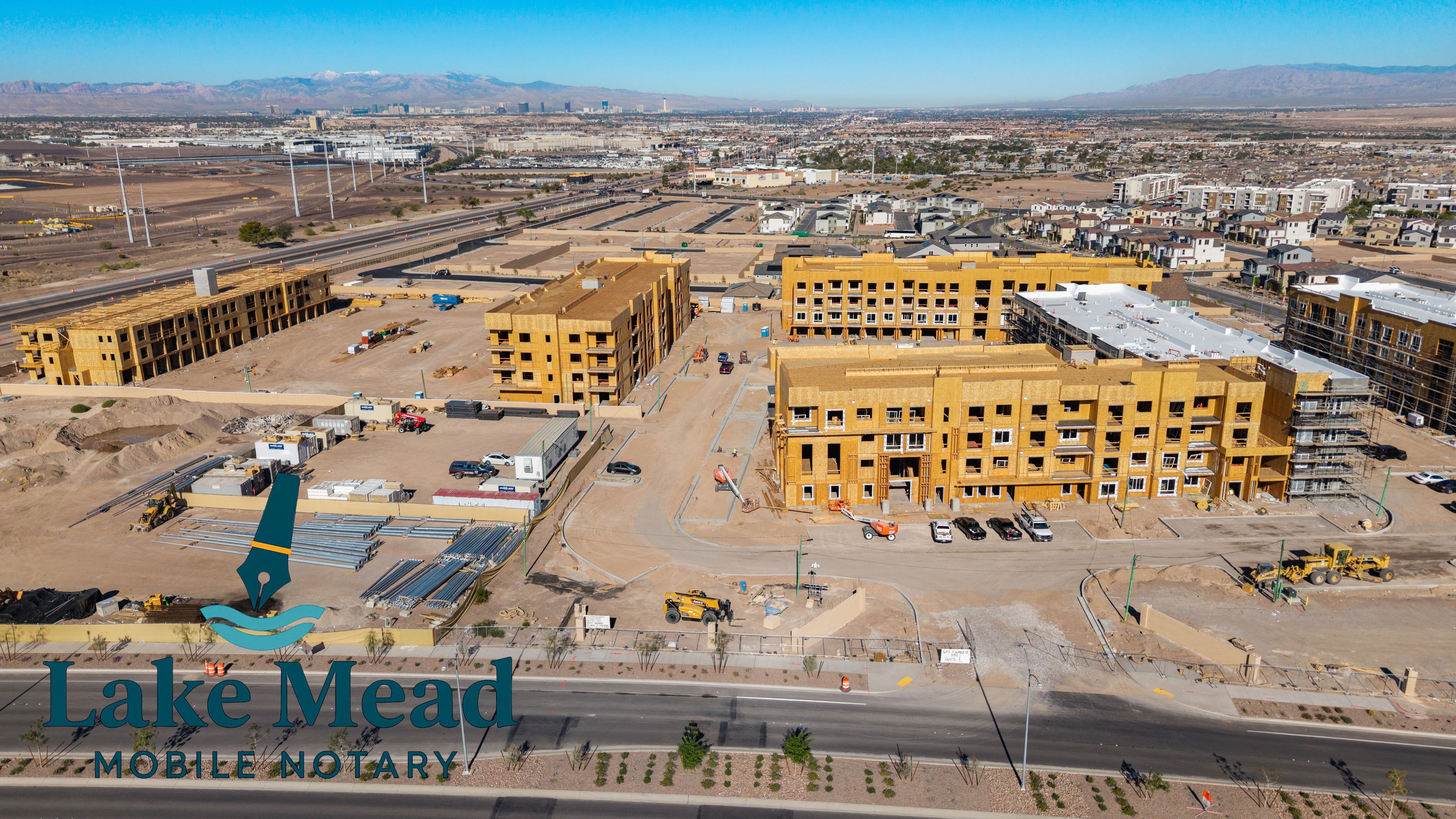 Aerial construction progress at mixed use complex in Henderson; wood framing, heavy equipment, Lake Mead Mobile Notary logo visible.