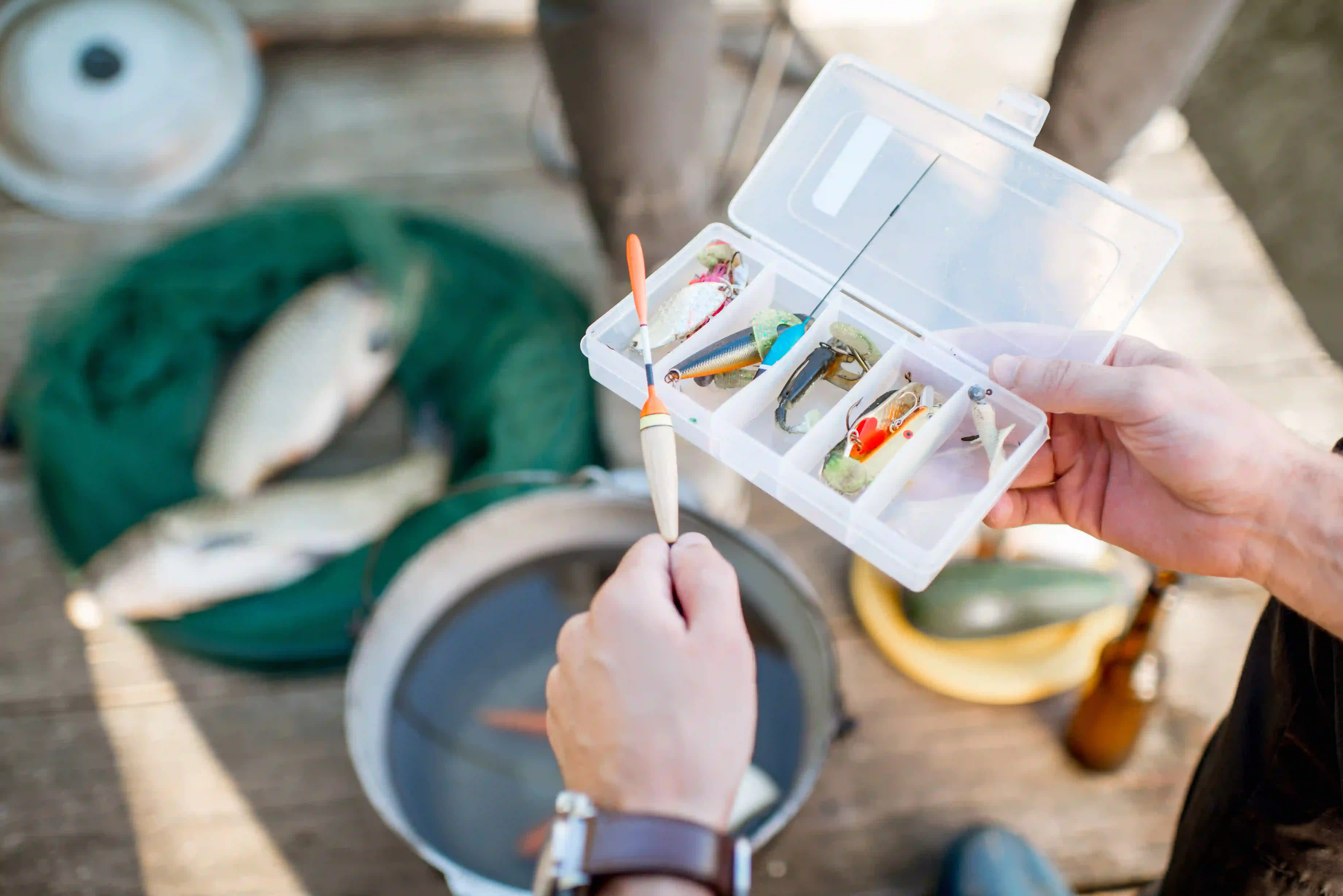 A man holding a box fill of bait used for fishing