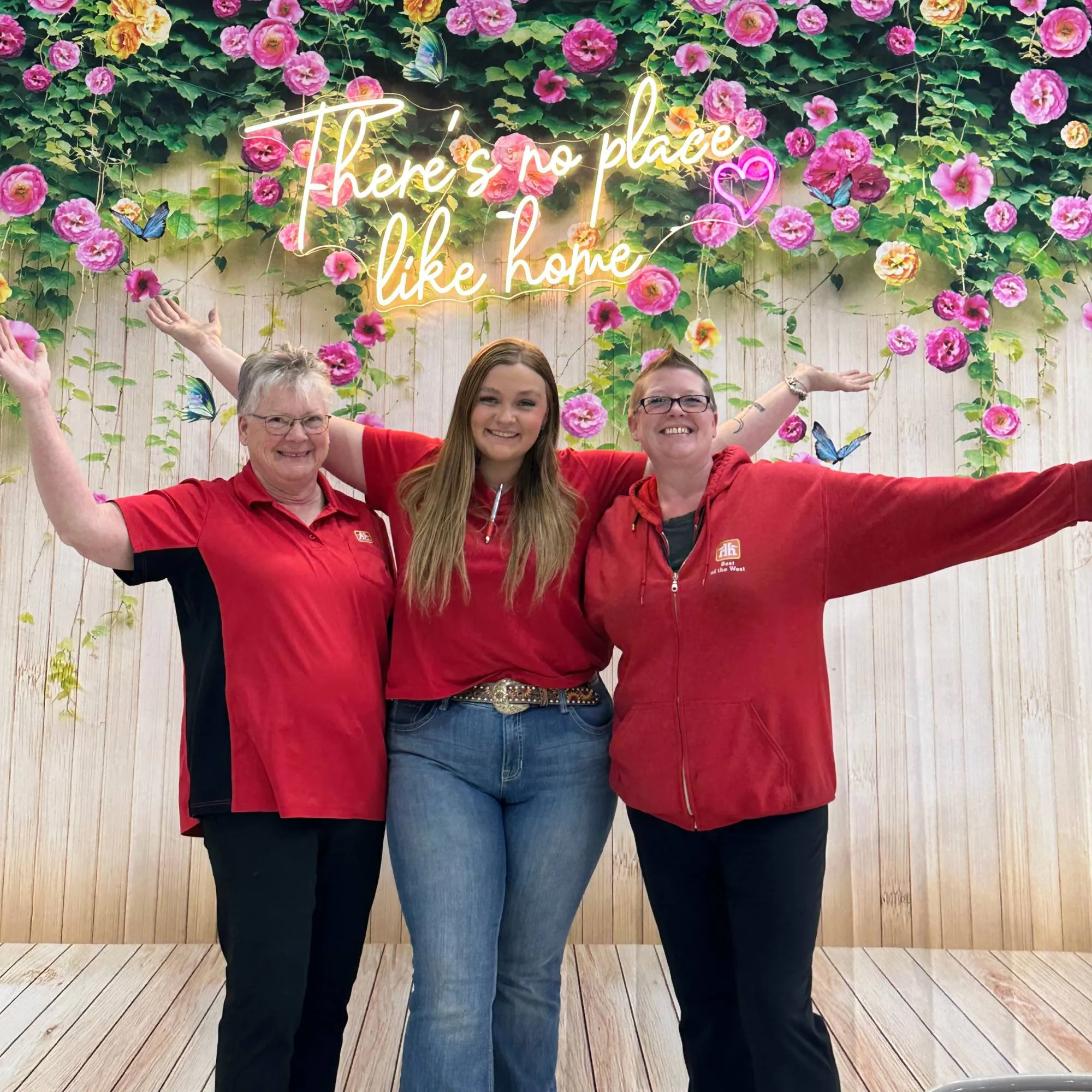 Group of female works posing in front of a flower backdrop