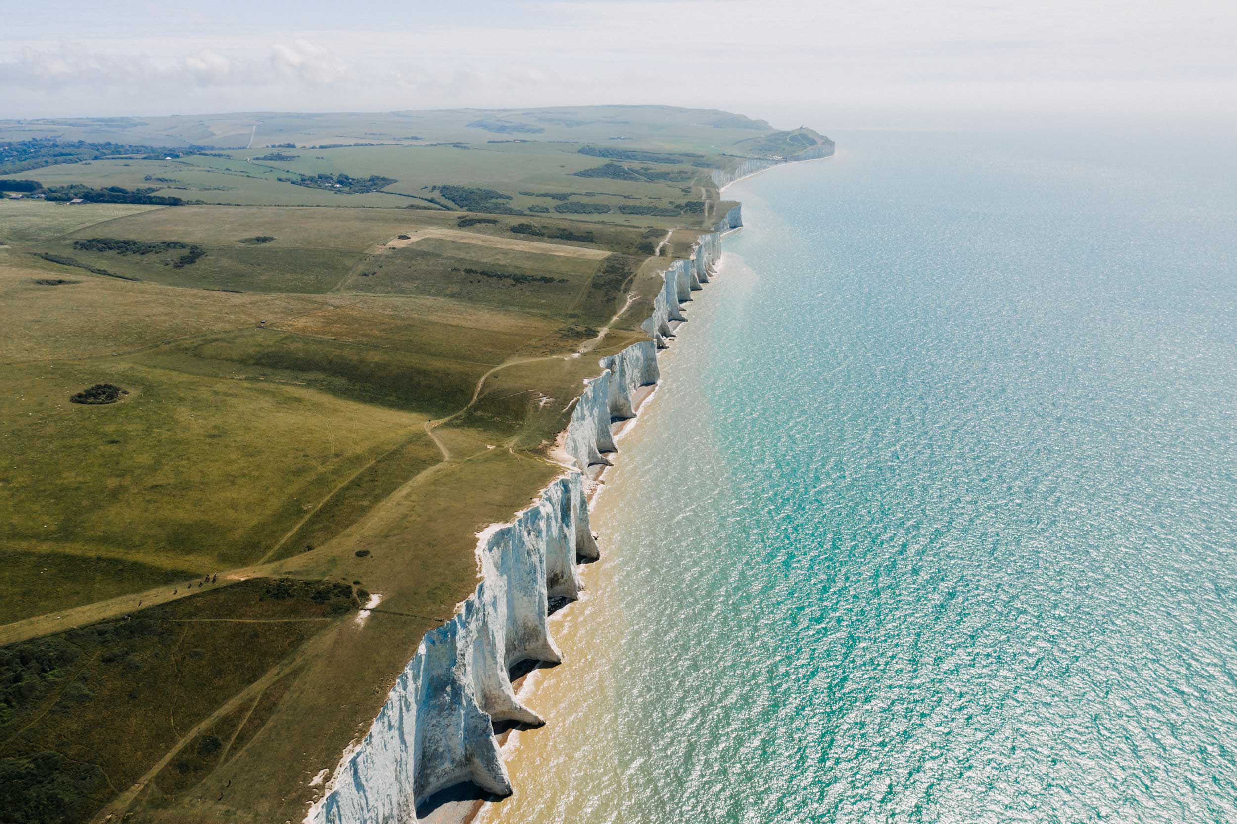 Cliffs overlooking the ocean with grassy fields on top, stretching into the distance.