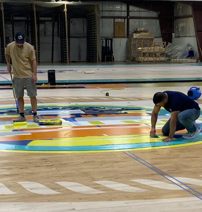 Employees painting center logo on the 2025 Tampa Bay tournament court. 