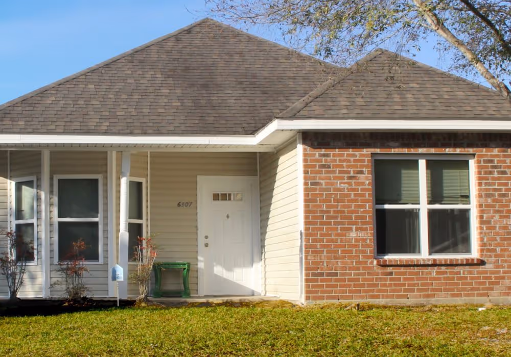 Single-story home with brick and siding exterior, hipped roof, front porch, and a clean, simple lawn.