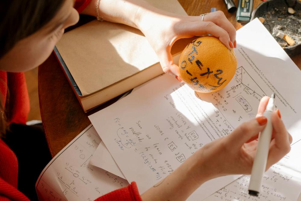Girl doing math using an orange.