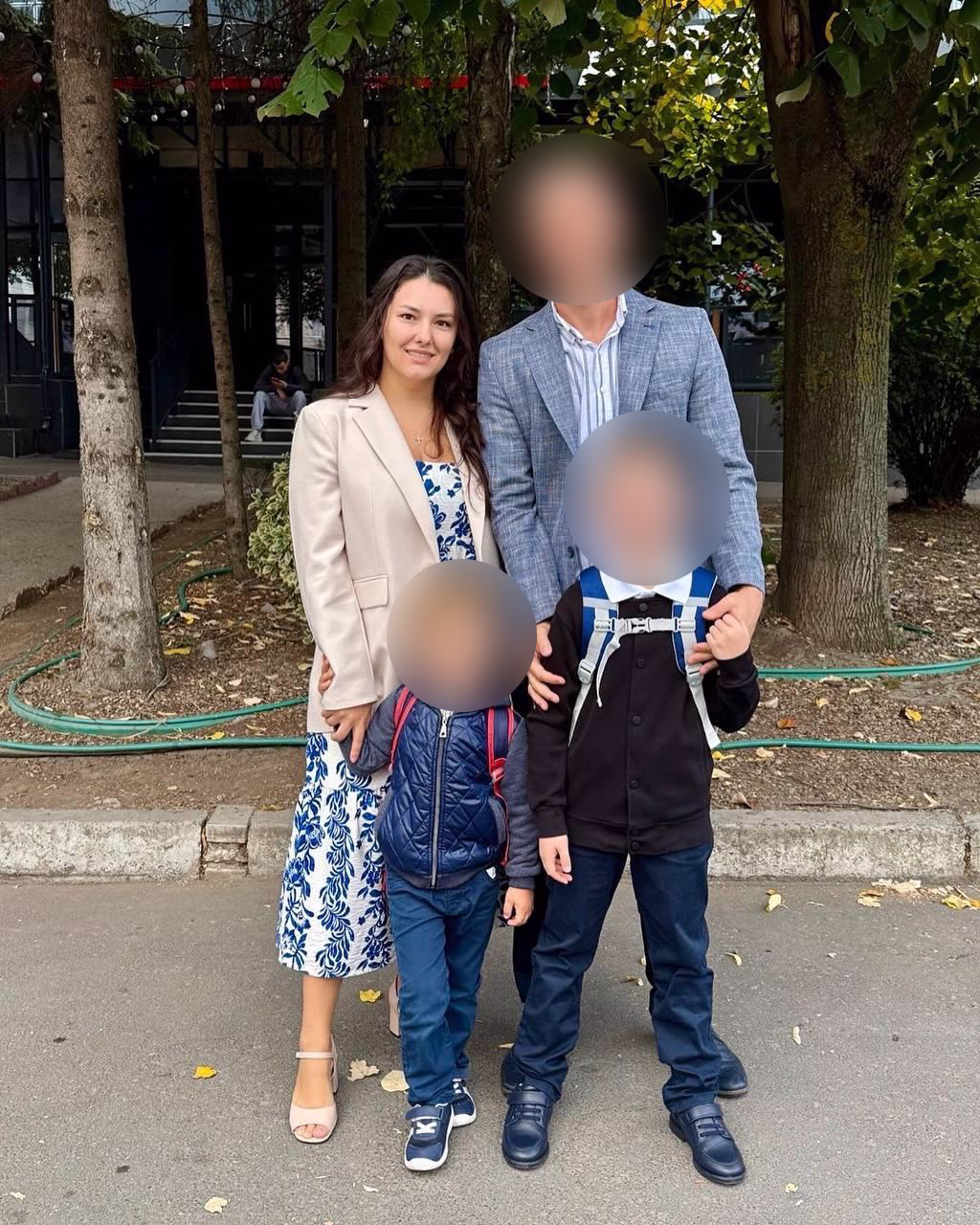 Женщина после преображения, в лёгком платье и пиджаке, улыбается, с мужем и детьми.