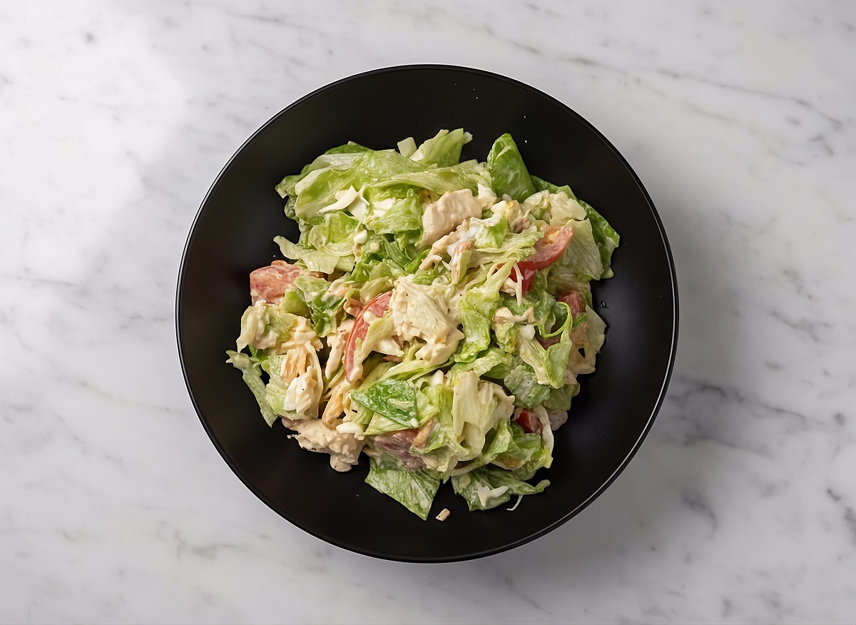 Салат из смеси овощей с обильной заправкой, с блестящими листьями.