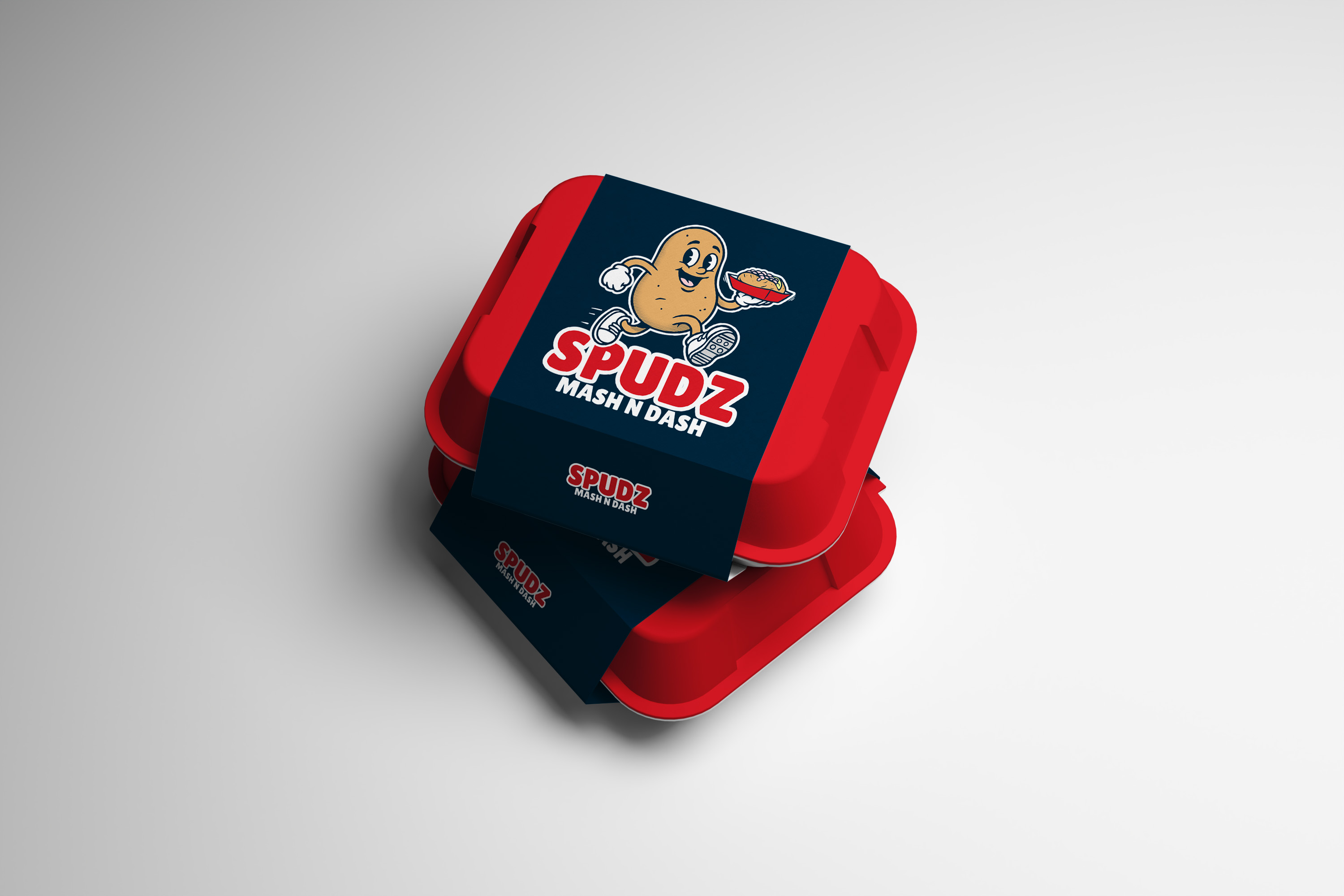 Deux boîtes rouges empilées avec une bande bleue affichant une pomme de terre animée tenant un bol de purée et le texte Spudz Mash N Dash.