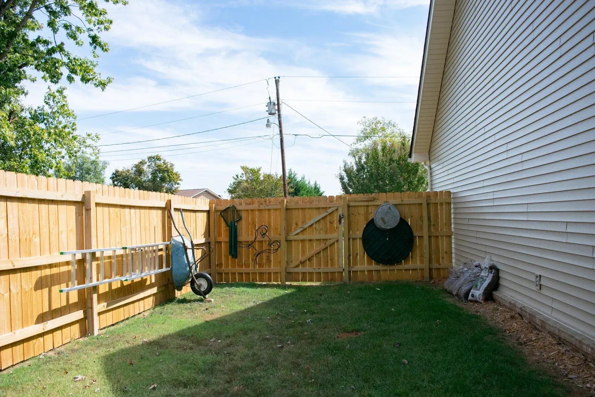 Wood privacy fence with a double drive gate in a Knoxville-area backyard, with a utility pole and overhead lines just beyond the fence line