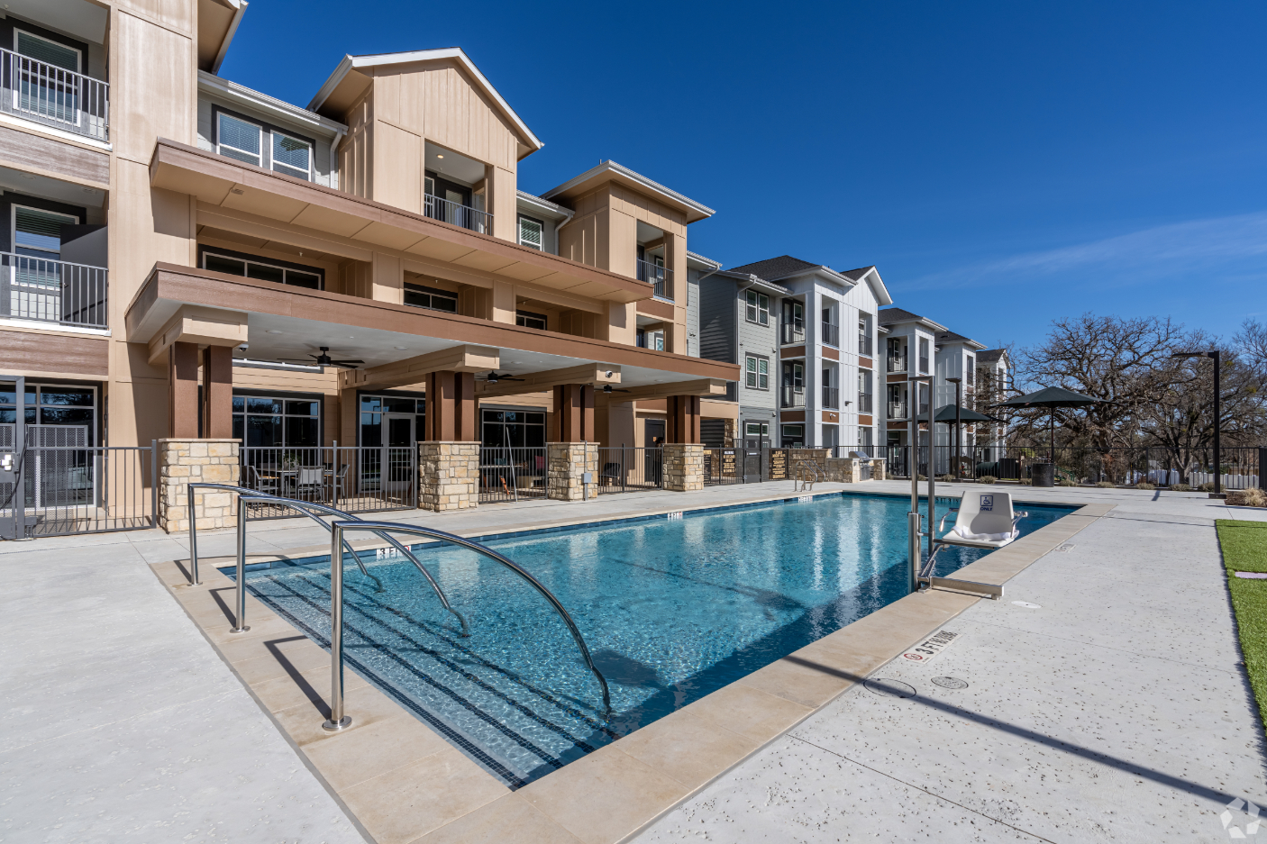 Exterior pool photo and grassy area with apartments surrounding 