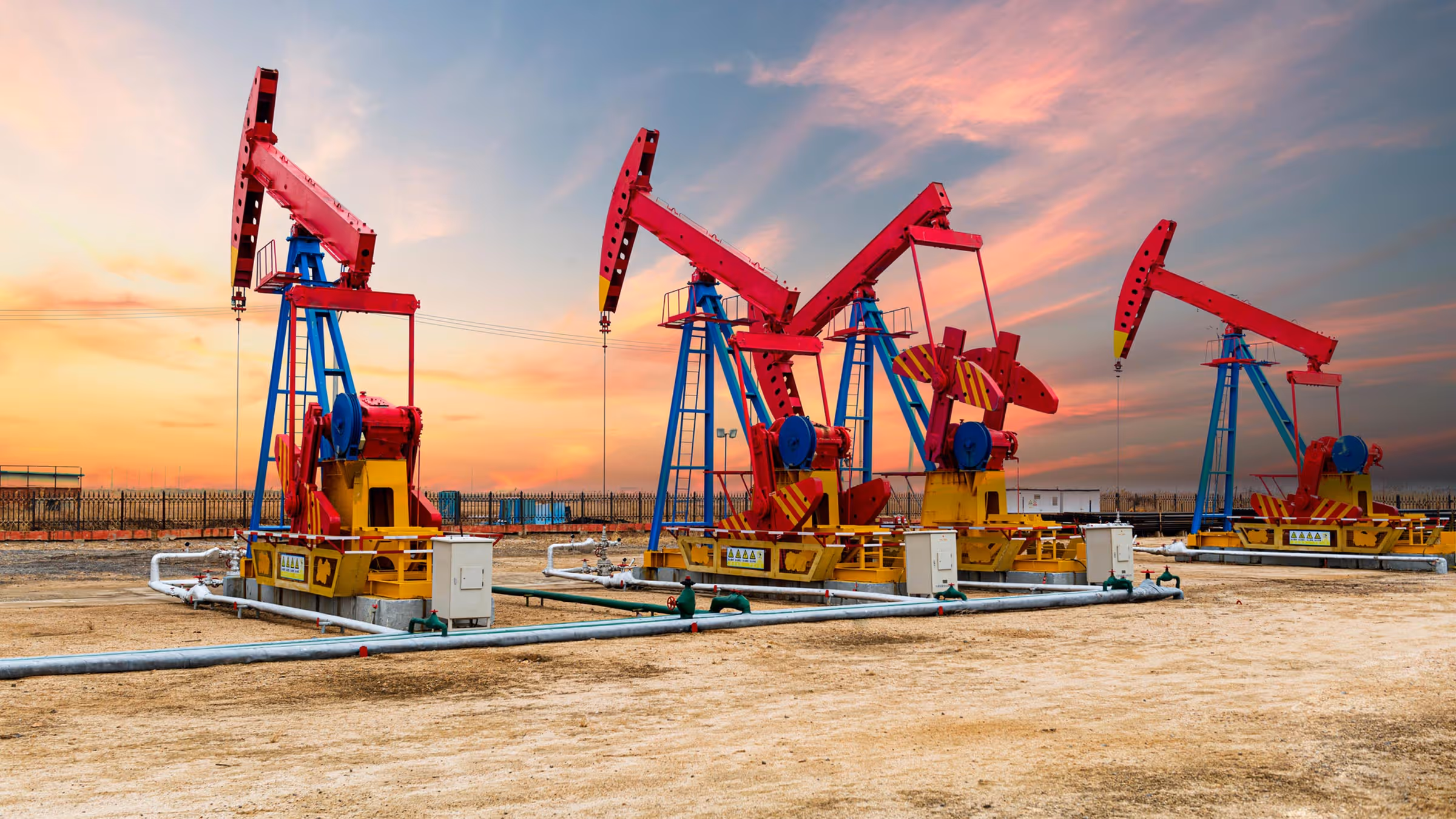 Red pump jacks in a field.