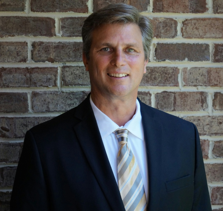 A man in a suit and tie standing in front of a brick wall.