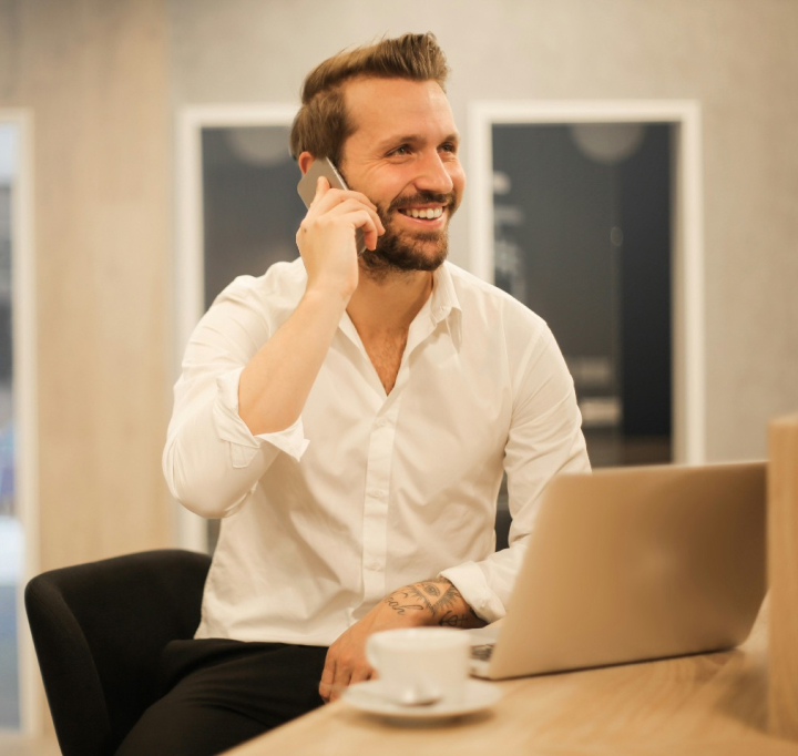 A man sitting at a table talking on a cell phone.